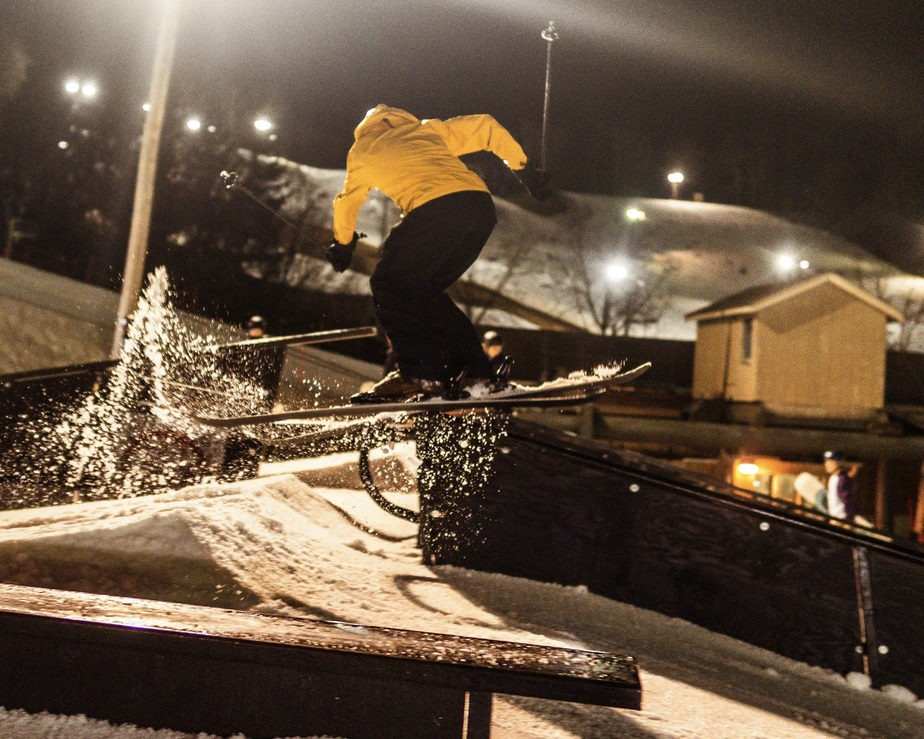 Night rail jam with snow spraying beneath the skis