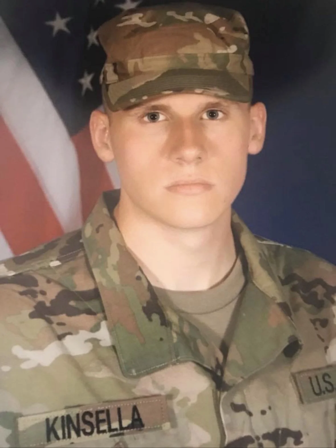 Connor in Army uniform in front of the American flag