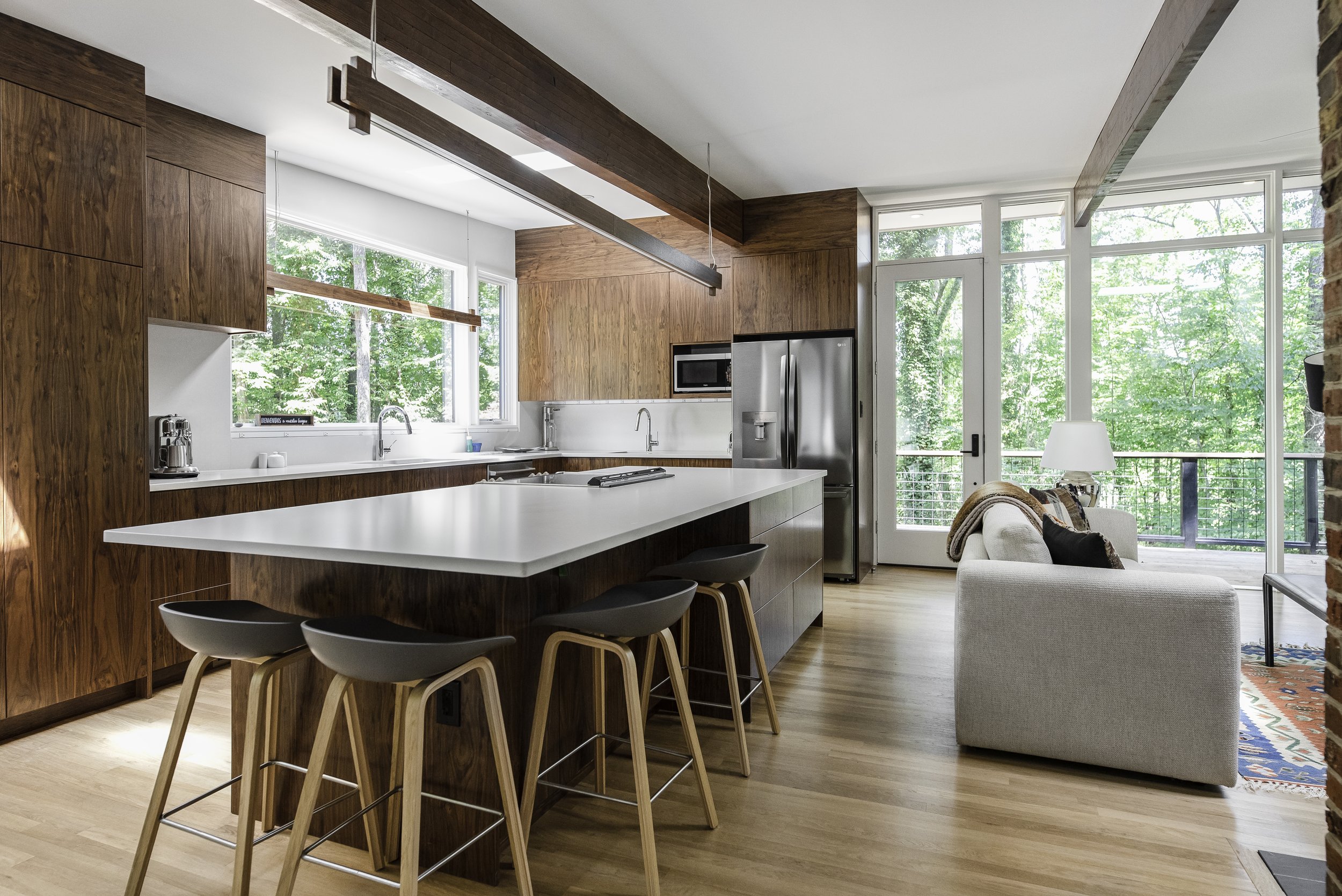Open modern kitchen with wood cabinets, white tile backsplash, granite counters, large kitchen island, and large floor to ceiling windows
