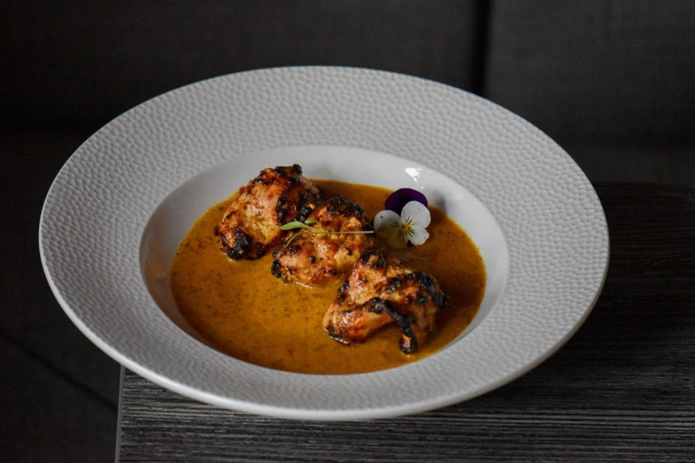 Mughlai Chicken in a yellow gravy in a white bowl