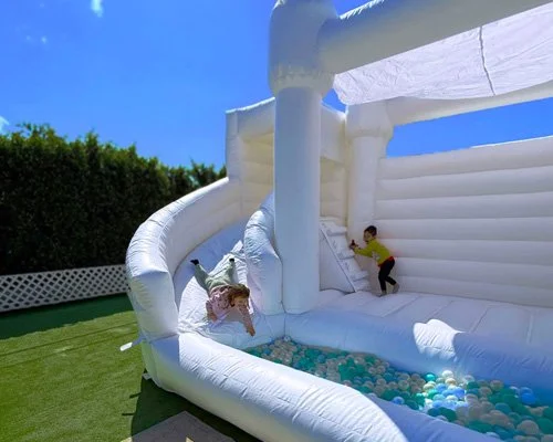 White bounce castle with deep ball pit and spiral slide — safe inflatable rental for birthday parties