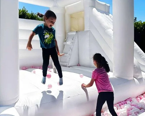 Kids enjoying Triple Delight bounce house with safe walls, slide, and colorful ball pit
