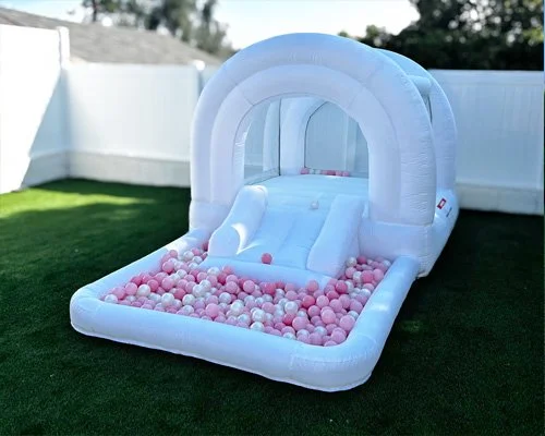 Compact white toddler bounce house with colorful balls — safe and fun backyard party idea