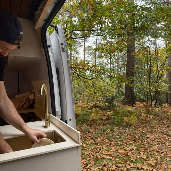 Washing up at the campervan sink in the woods