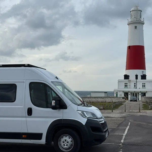 Campervan beside a red and white lighthouse