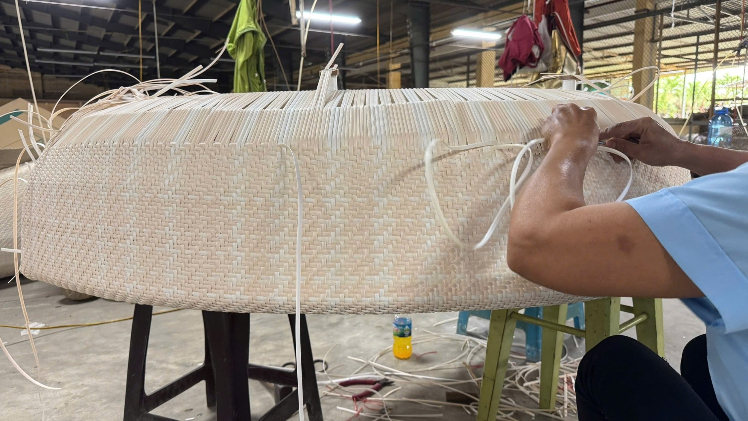 Artisans weaving rattan furniture in a clean Vietnam factory near Nha Trang, with sustainable materials and export crates, supporting wholesale furniture sourcing in 2025
