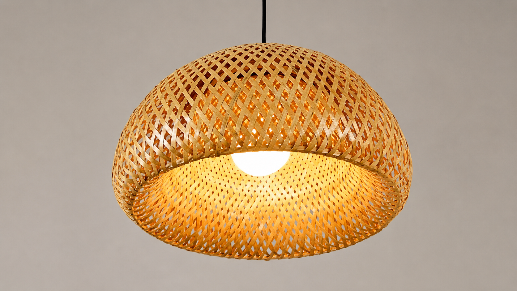 Handwoven bamboo pendant shade with double-layer crosshatch weave pattern, glowing with warm interior light