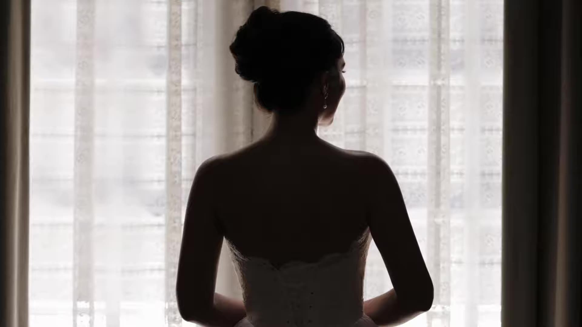 Silhouette of Anna in a strapless gown in front of a lace curtained window getting ready in Austin, Texas