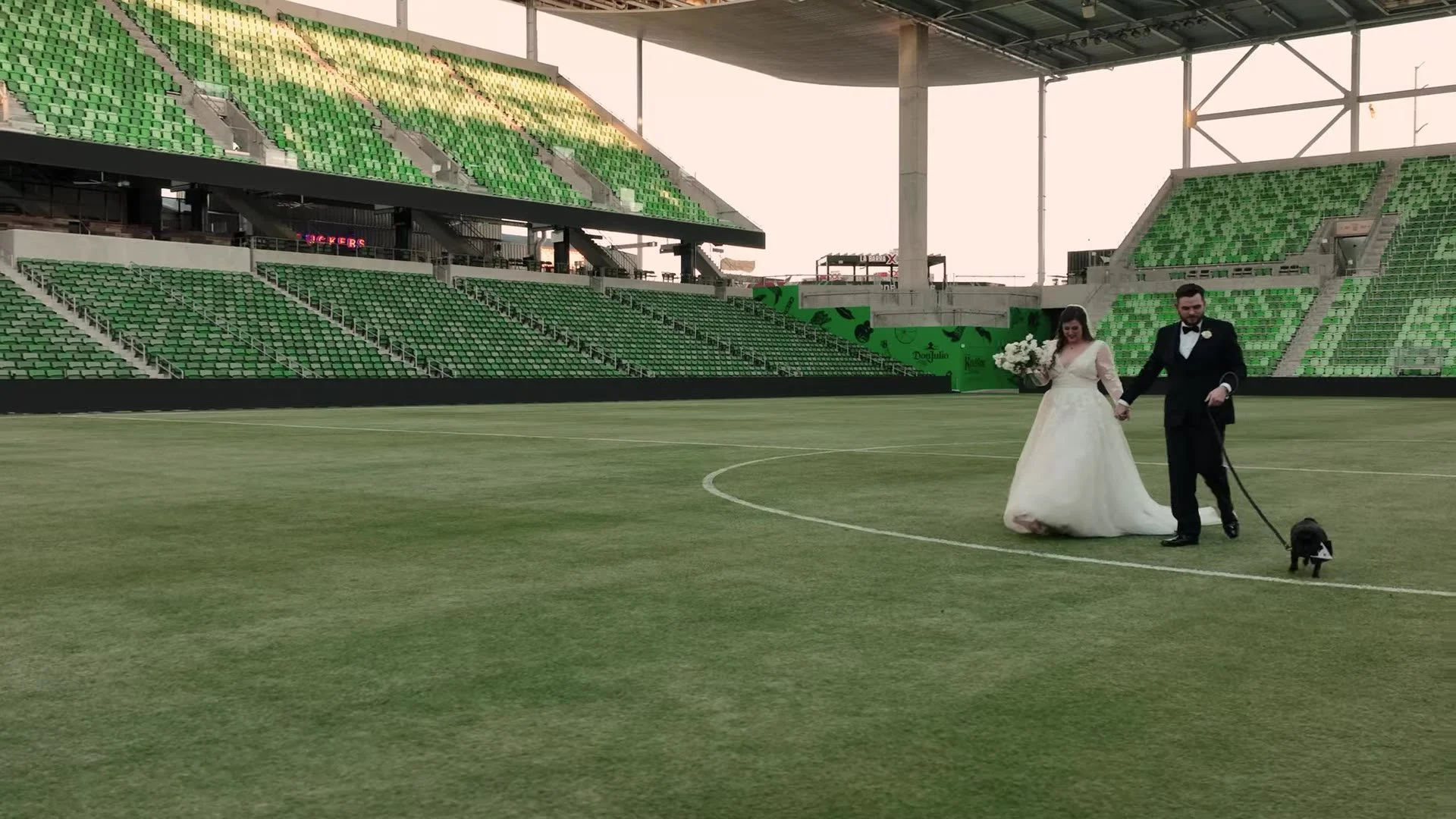 Gabby and Nic walking their dog Mackie across the soccer pitch at Q2 Stadium in Austin, Texas