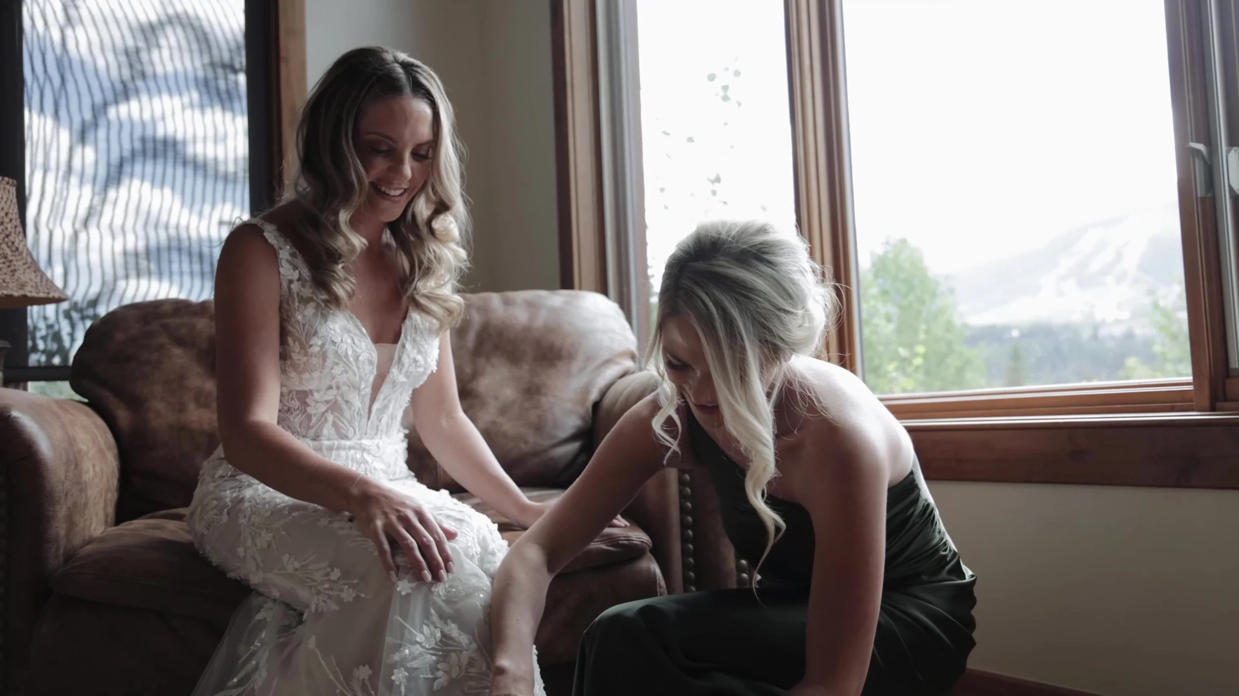 Caitlin getting ready with a bridesmaid and Colorado mountains in the window at Breckenridge