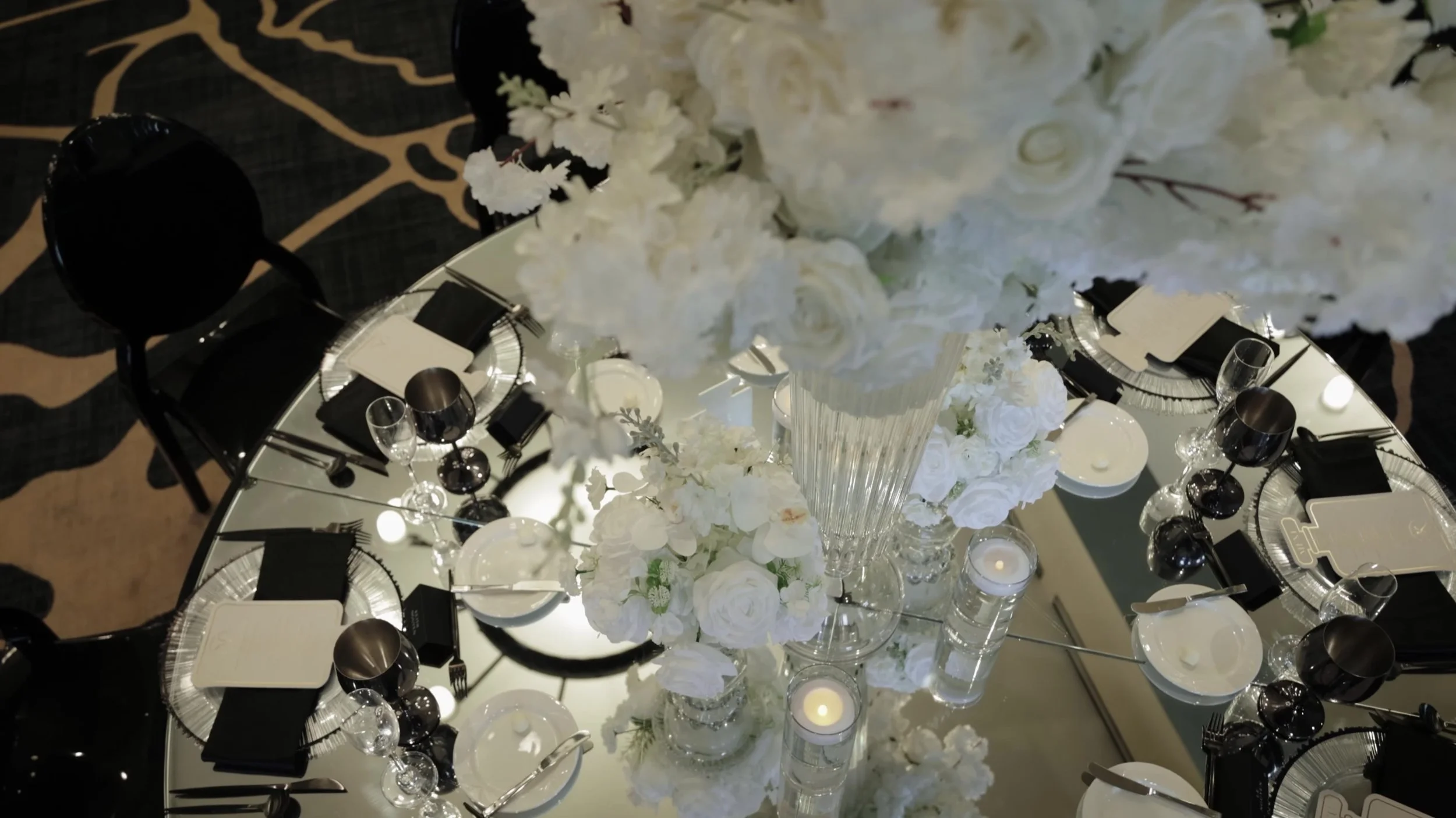 Mirrored reception table with black plates white florals and candles at Barton Creek Austin