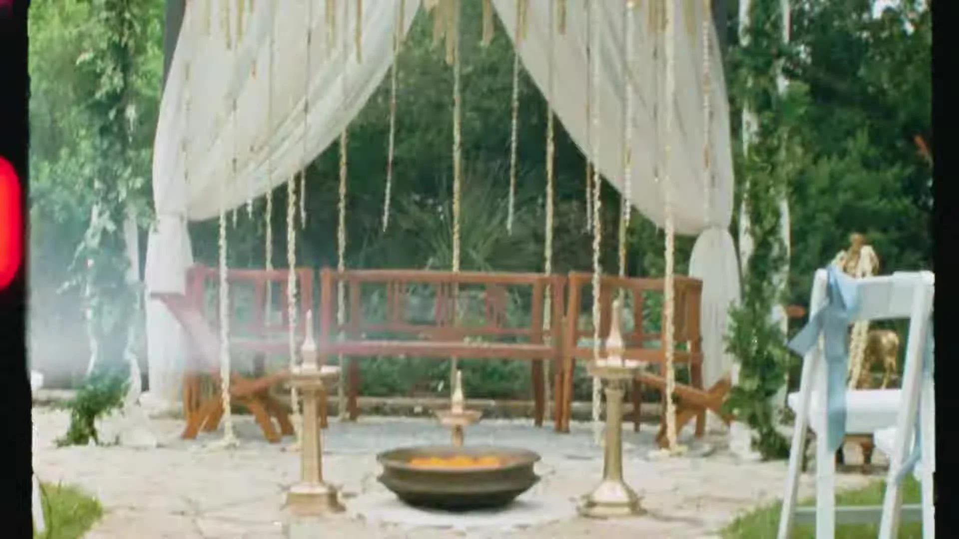 Empty outdoor mandap with white drapery, hanging jasmine strands, marigold bowl, and brass lamps at The Terrace Club in Austin