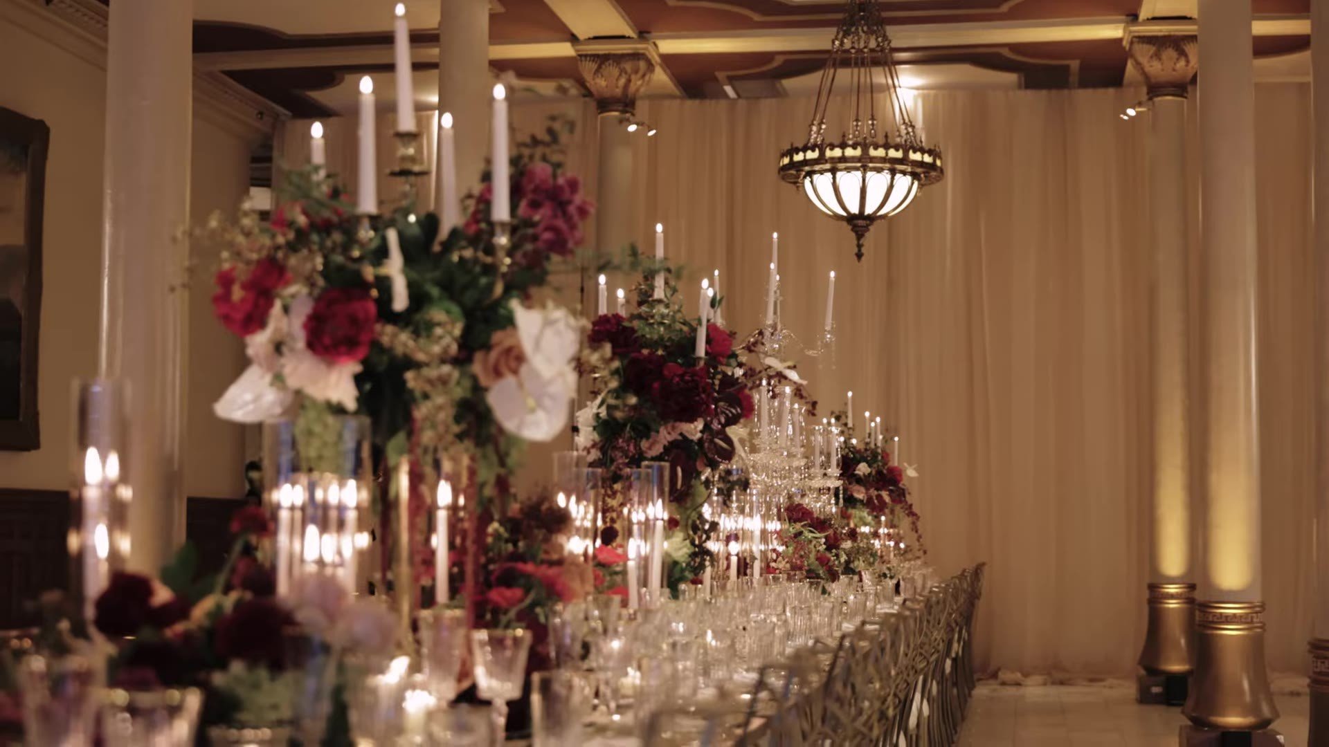 Long candlelit reception table with burgundy florals in a ballroom at The Driskill Hotel in Austin, Texas