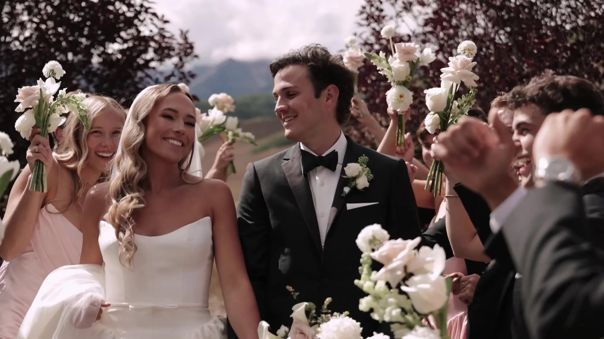 Becca and Colton walking through a cheering wedding party at Crested Butte Wedding Garden in Colorado
