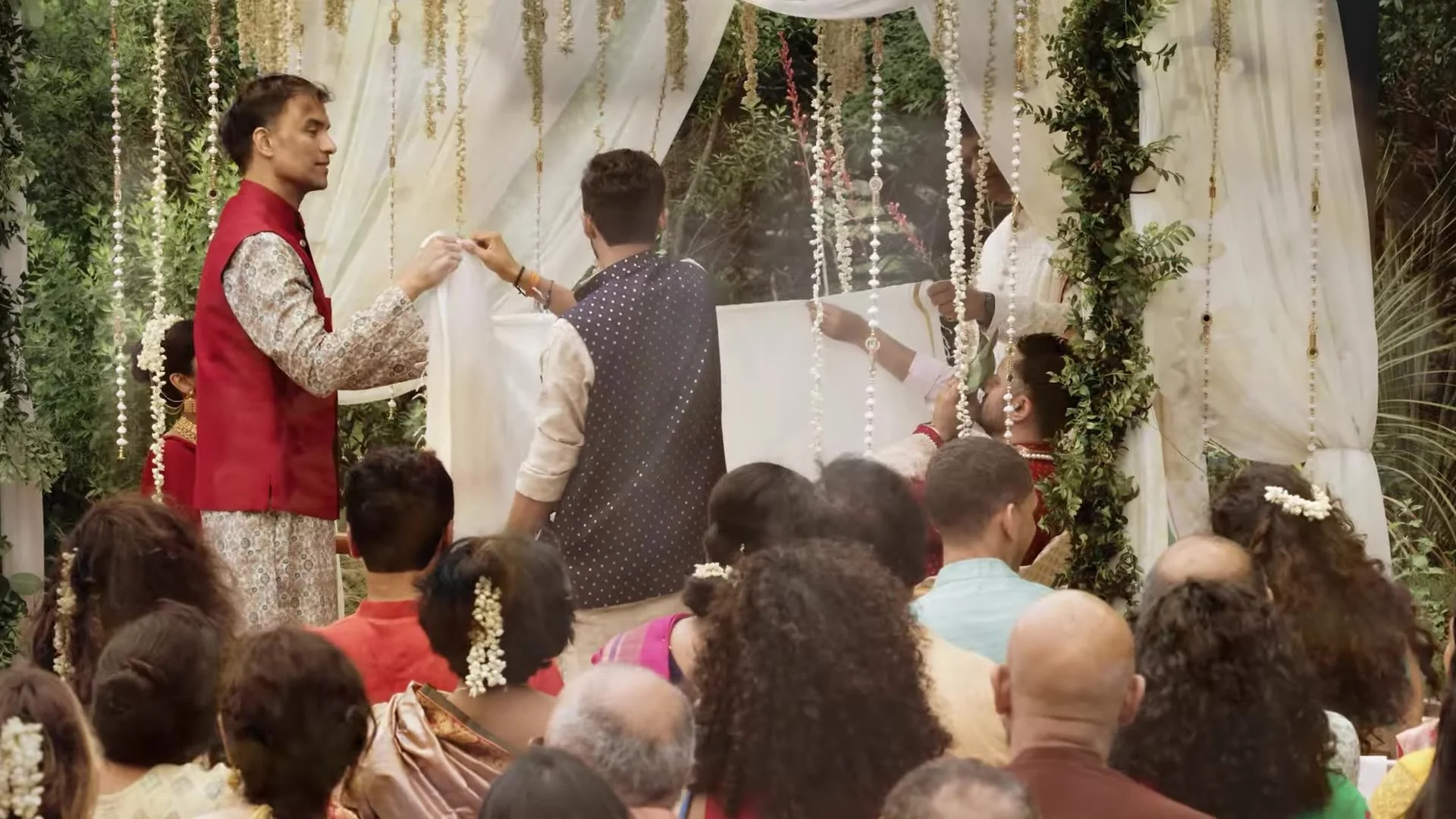 Guests holding a white antarpat cloth under the outdoor mandap during Bhavim and Mala's Indian wedding ceremony in Austin, Texas