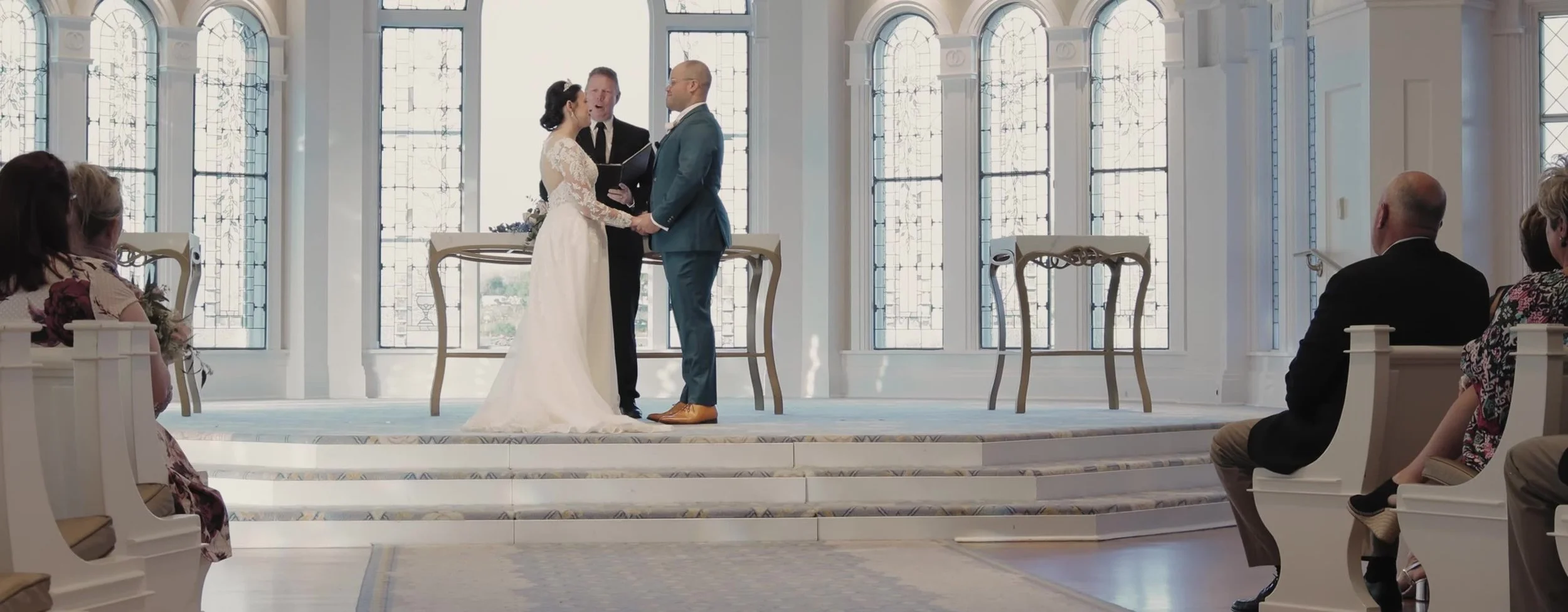Wide ceremony inside Disney's Wedding Pavilion, couple at the altar, guests in white pews, blue aisle runner
