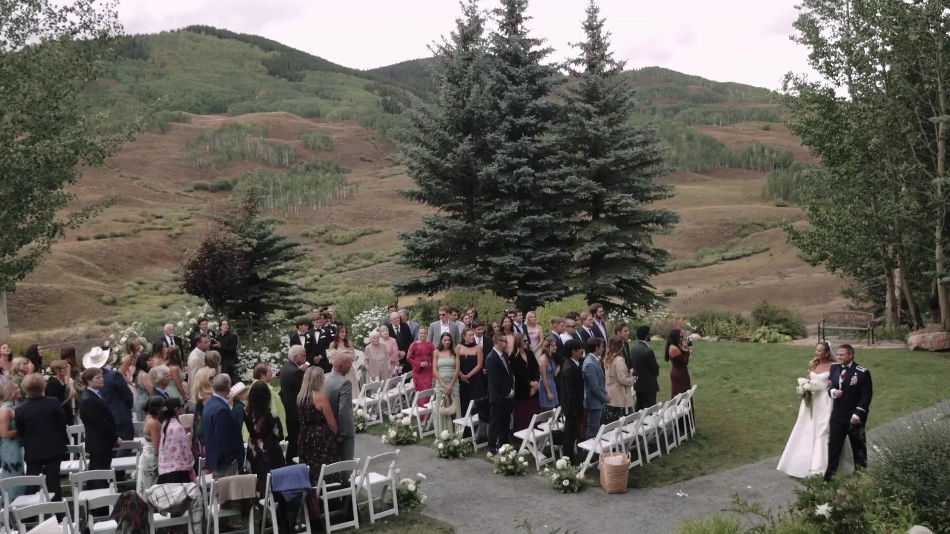 Bride walking the aisle at Crested Butte Wedding Garden as guests stand against Colorado hills