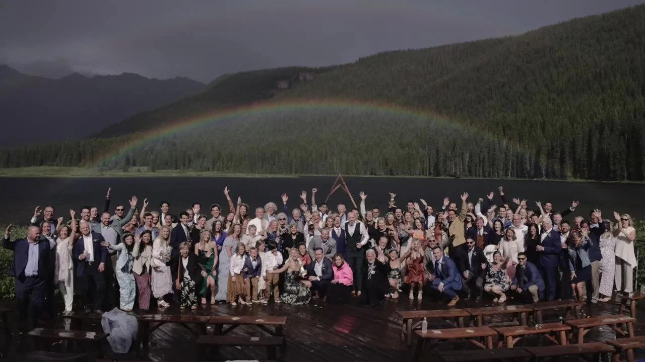Wedding guests cheering on the wet Piney River Ranch deck with a rainbow over Piney Lake