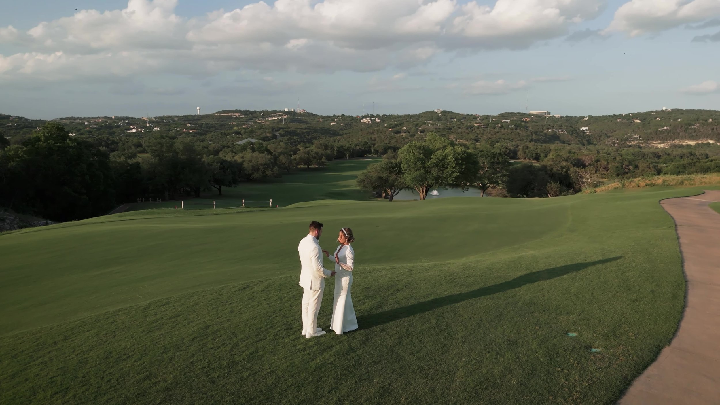 Keely and Jay in white standing on the green golf course at Barton Creek Country Club in Austin Texas Hill Country
