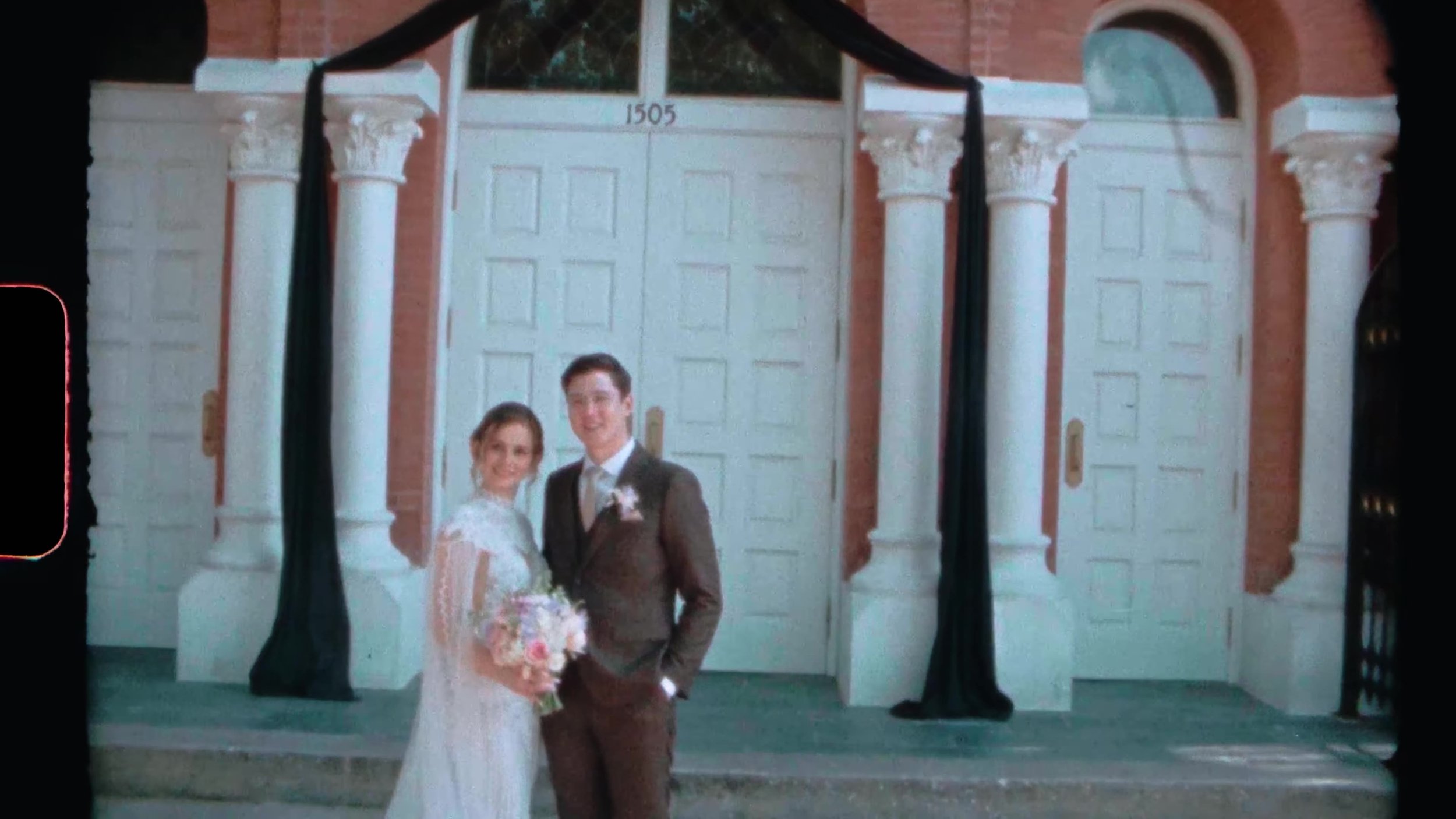 Bride and groom standing at white doors marked 1505 outside a red brick Houston wedding venue on film