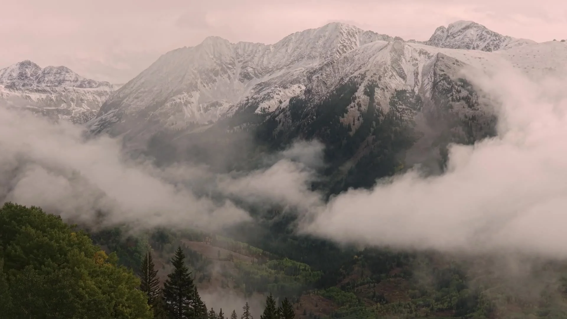 Snow dusted Crested Butte peaks in mist with evergreen slopes in Colorado