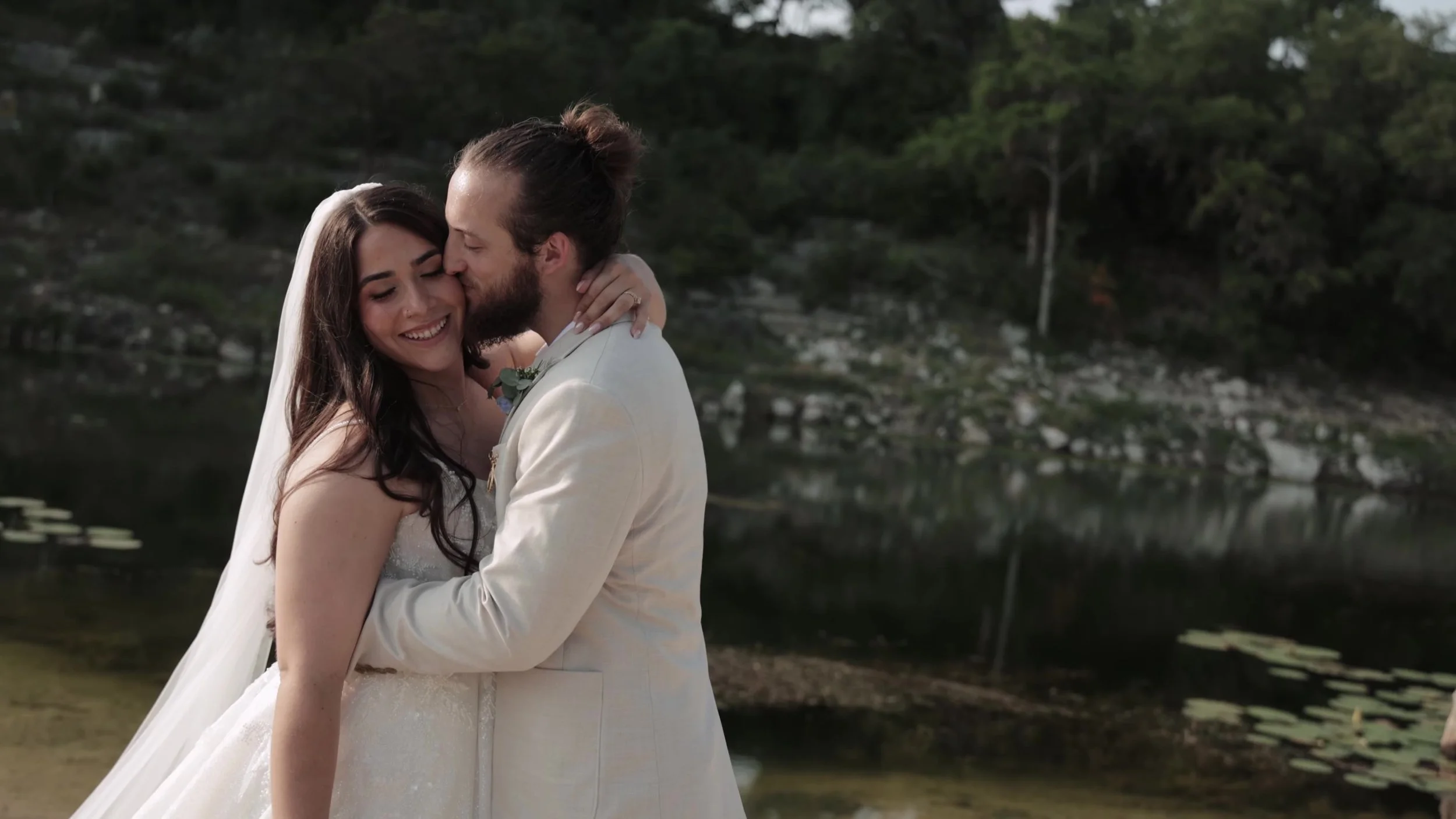 Peter kissing Kiyara cheek by the water at Videre Estate in Texas Hill Country near Austin