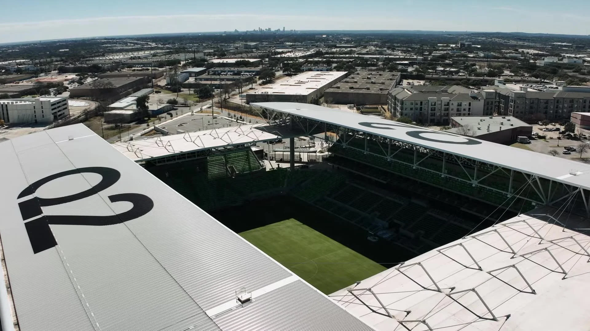 Aerial view of Q2 Stadium roof with Q2 logo and downtown Austin skyline beyond