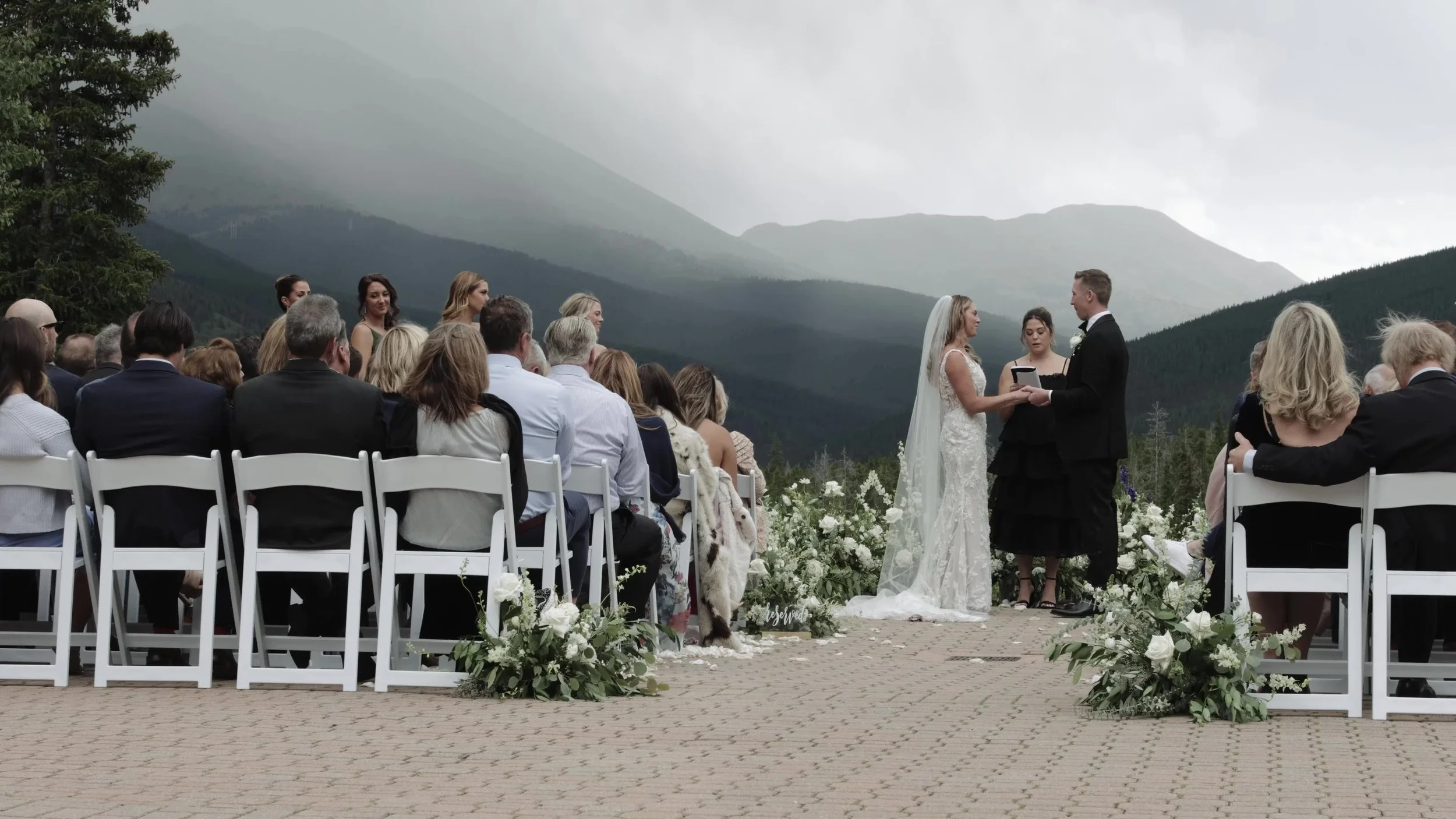 Caitlin and Matthew exchanging vows outdoors at Ten Mile Station with Colorado mountains behind them