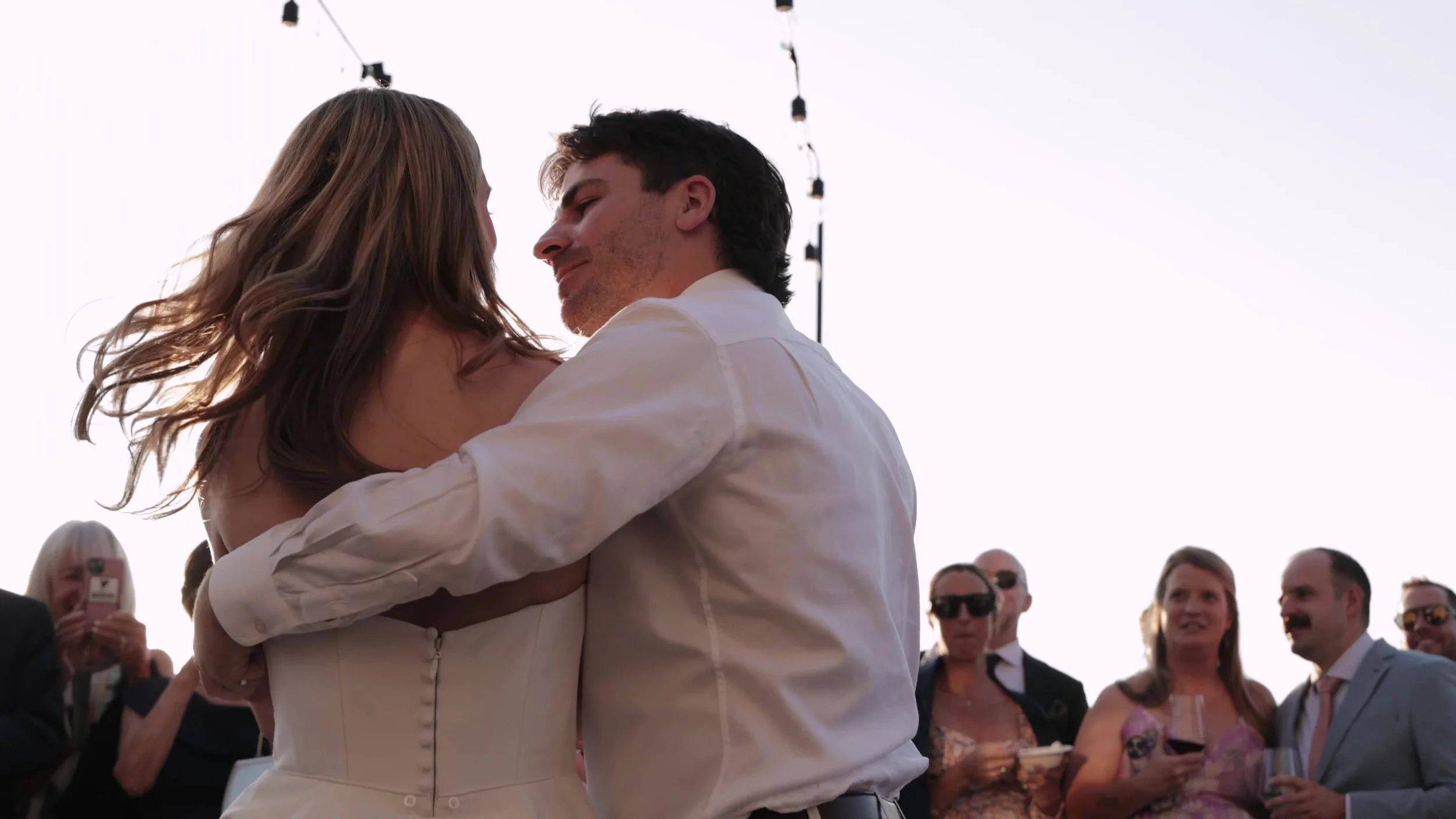 Couple in a close dance at dusk at Northstar Gatherings in Idaho Springs, Colorado, string lights above the guests