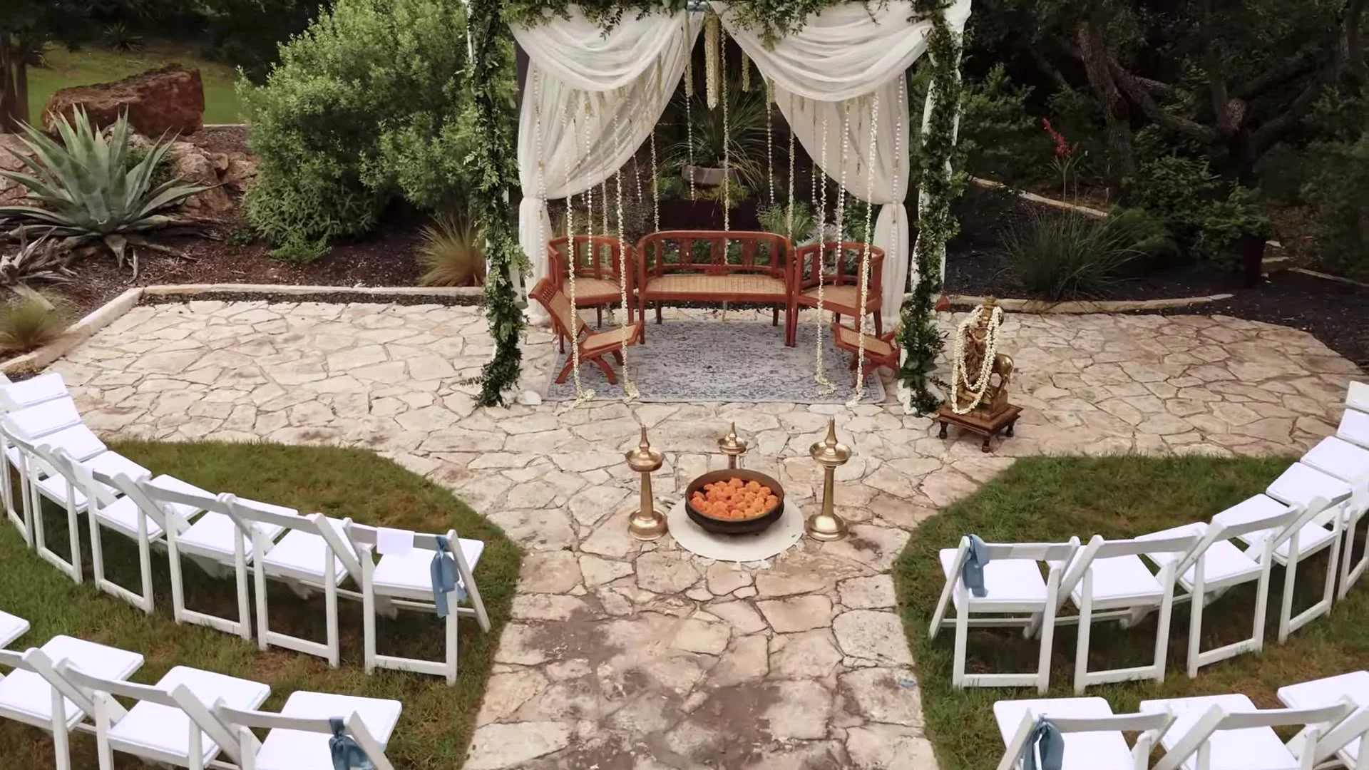 Overhead view of the outdoor mandap, white chairs, marigold bowl, and brass lamps at The Terrace Club Indian wedding in Austin, Texas