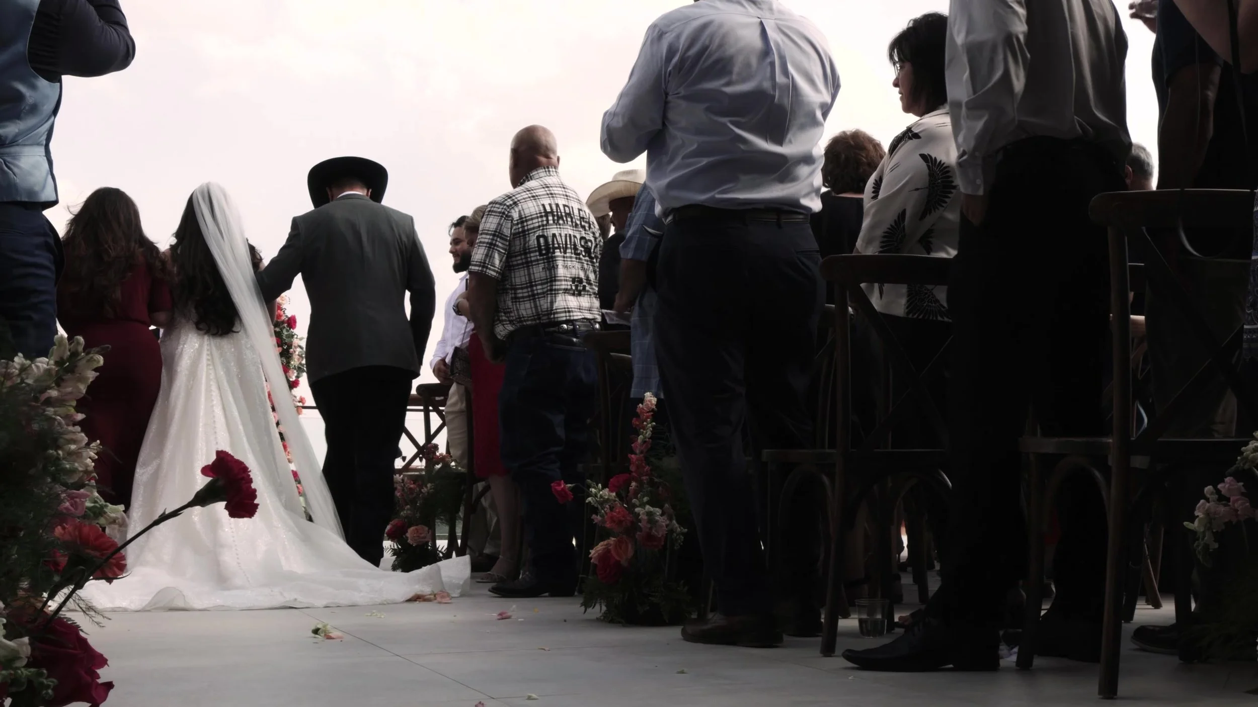 Peter and Kiyara at the floral altar seen through seated guests at Videre Estate near Austin