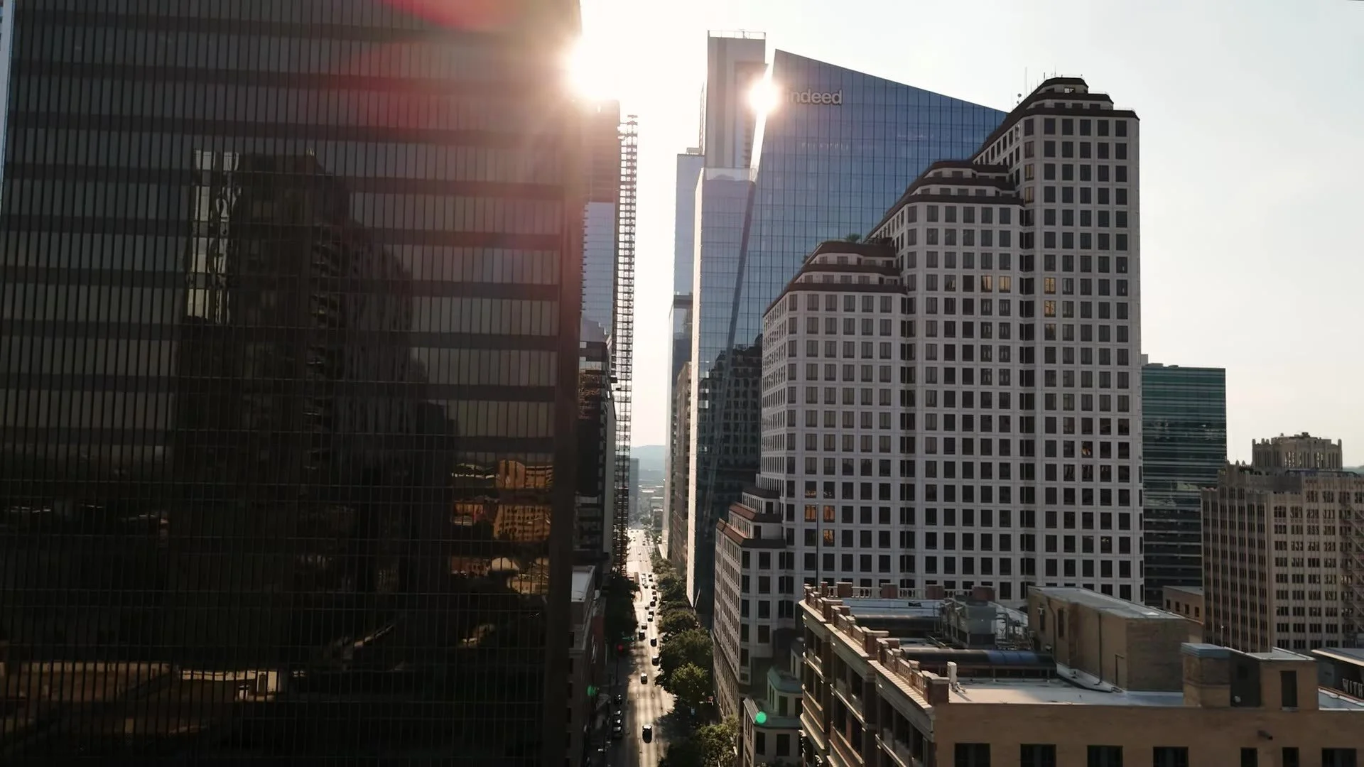 Downtown Austin Texas street between skyscrapers with sun flare at the end of the canyon