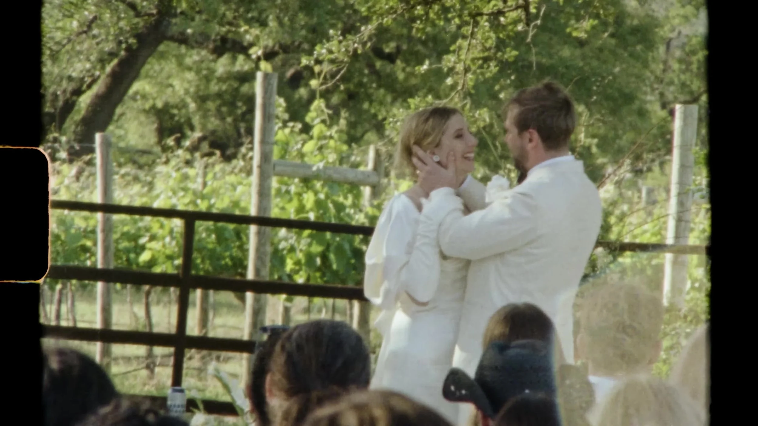 Sarah in white gloves standing with her partner in a white tuxedo at Camp Lucy Vineyards in Austin, Texas