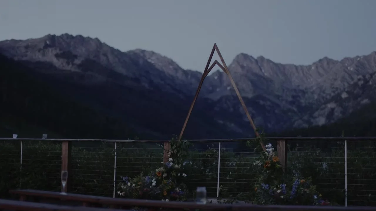Empty dusk ceremony at Piney River Ranch, triangular wood arch and Gore Range silhouette