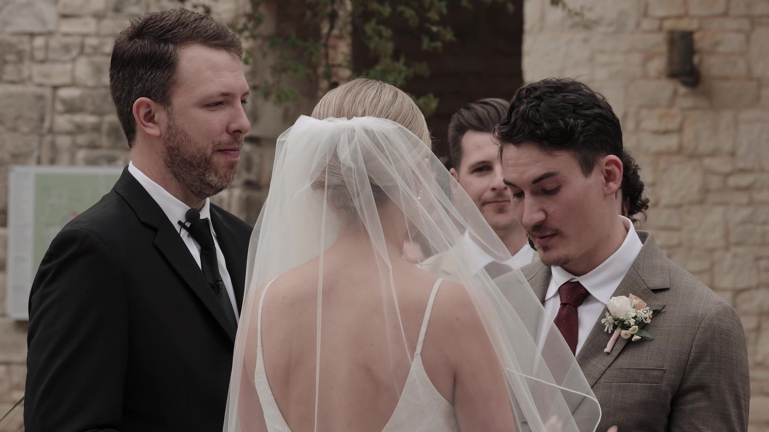 Chris looking at Heather during vows with her veil in the foreground at Lady Bird Johnson Wildflower Center in Austin, Texas