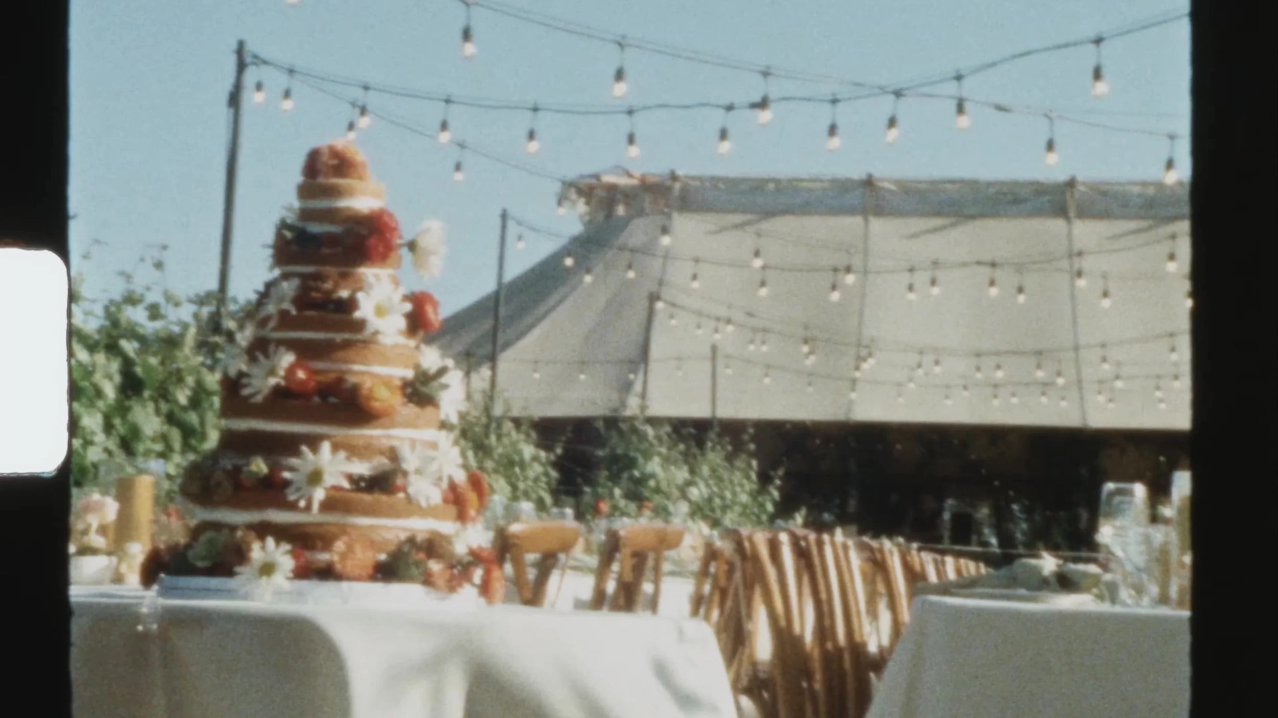 Naked wedding cake with berries and couple toppers at Camp Lucy Vineyards in Austin, Texas