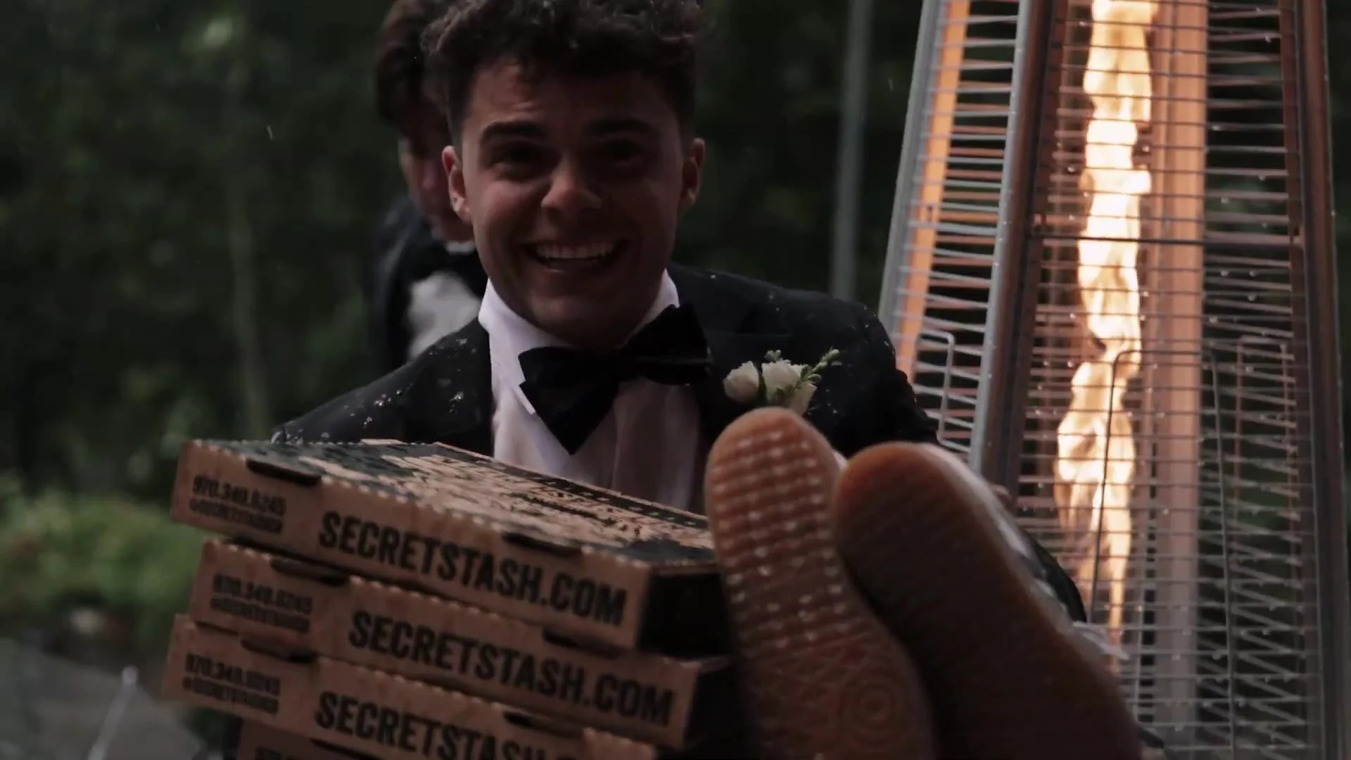 Guest in a tuxedo holding Secret Stash pizza boxes at a Crested Butte Wedding Garden reception in Colorado