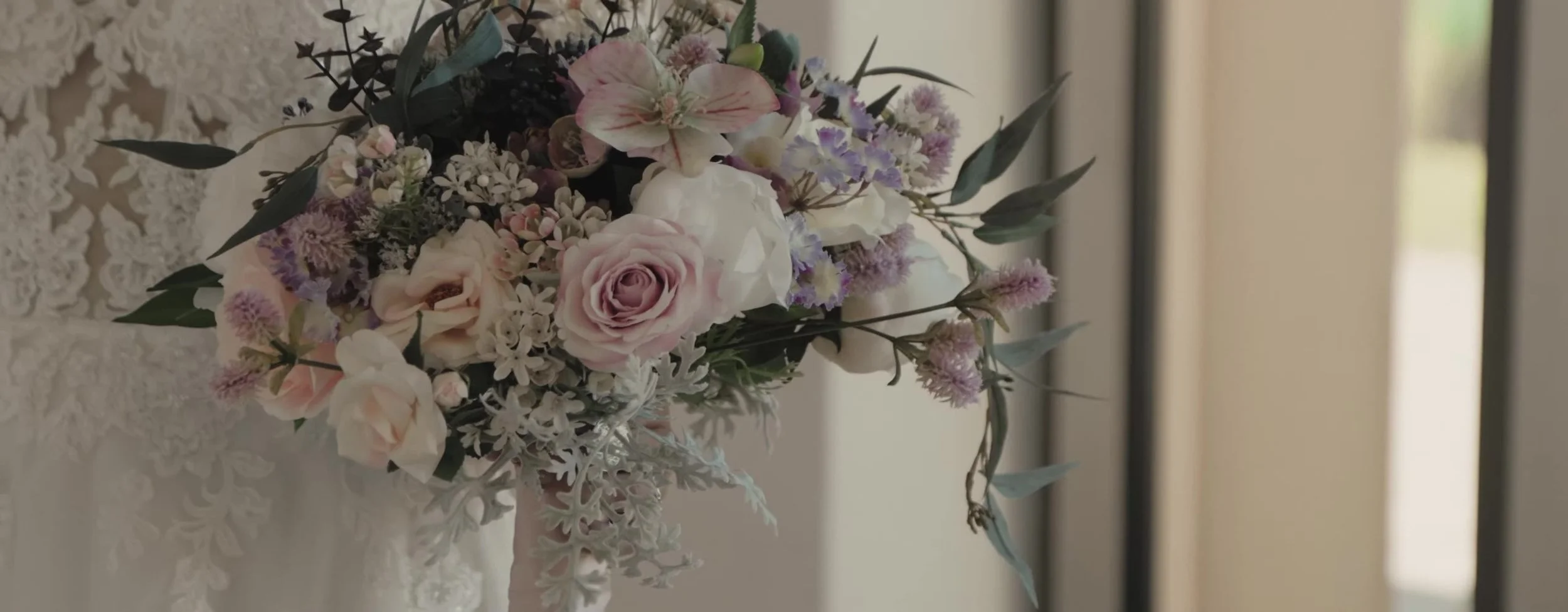 Bridal bouquet of dusty pink roses, white blooms, lavender sprigs, and dark greenery