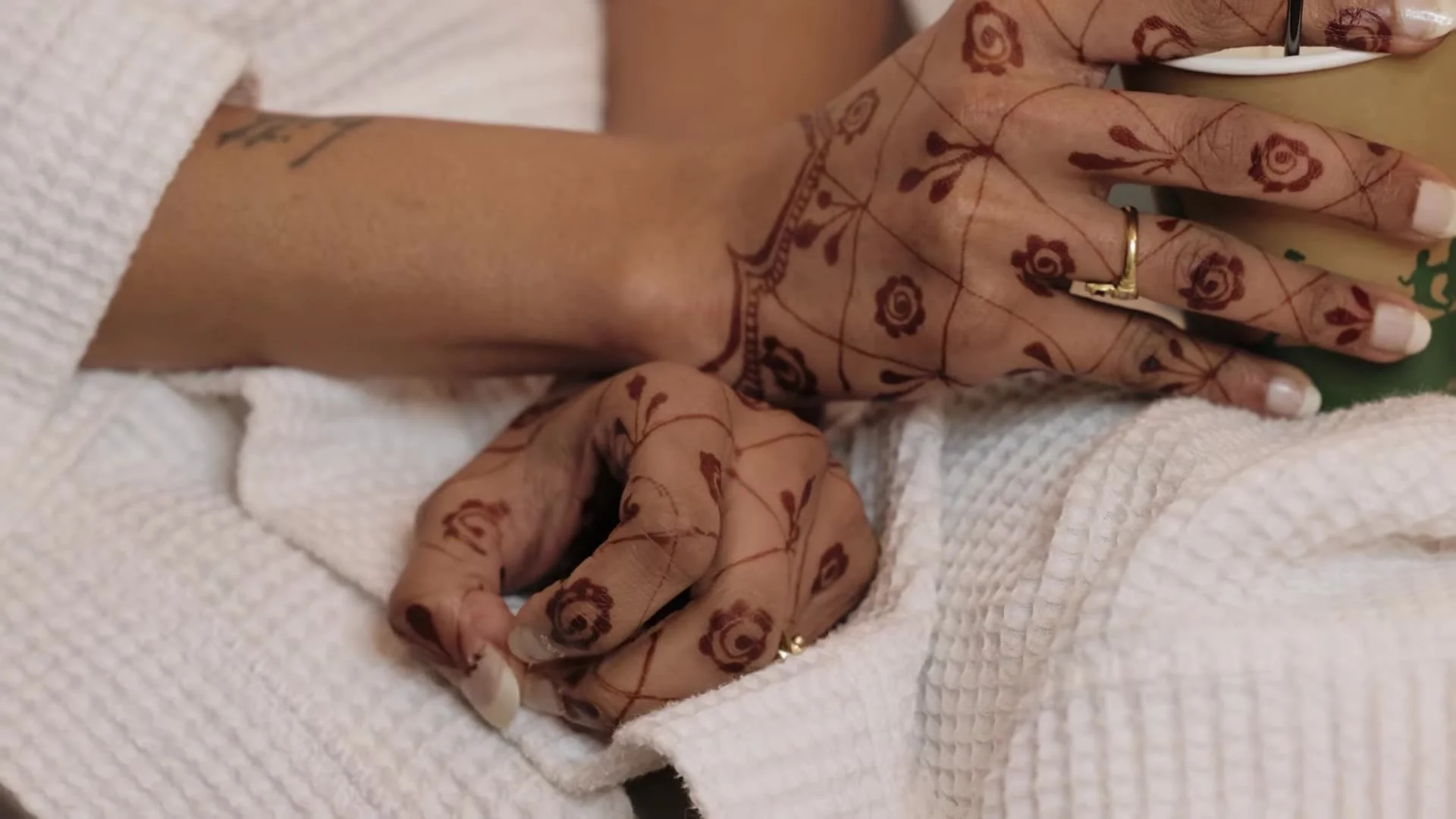 Close up of Mala's hands with intricate mehndi henna designs while getting ready in a white robe before her Austin Indian wedding