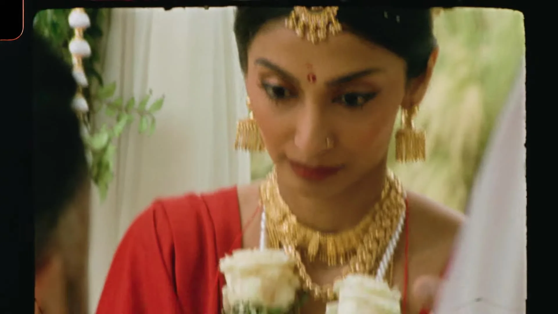 Close up of Mala in a red sari with gold maang tikka, jhumka earrings, and pearl necklace during the Indian ceremony in Austin