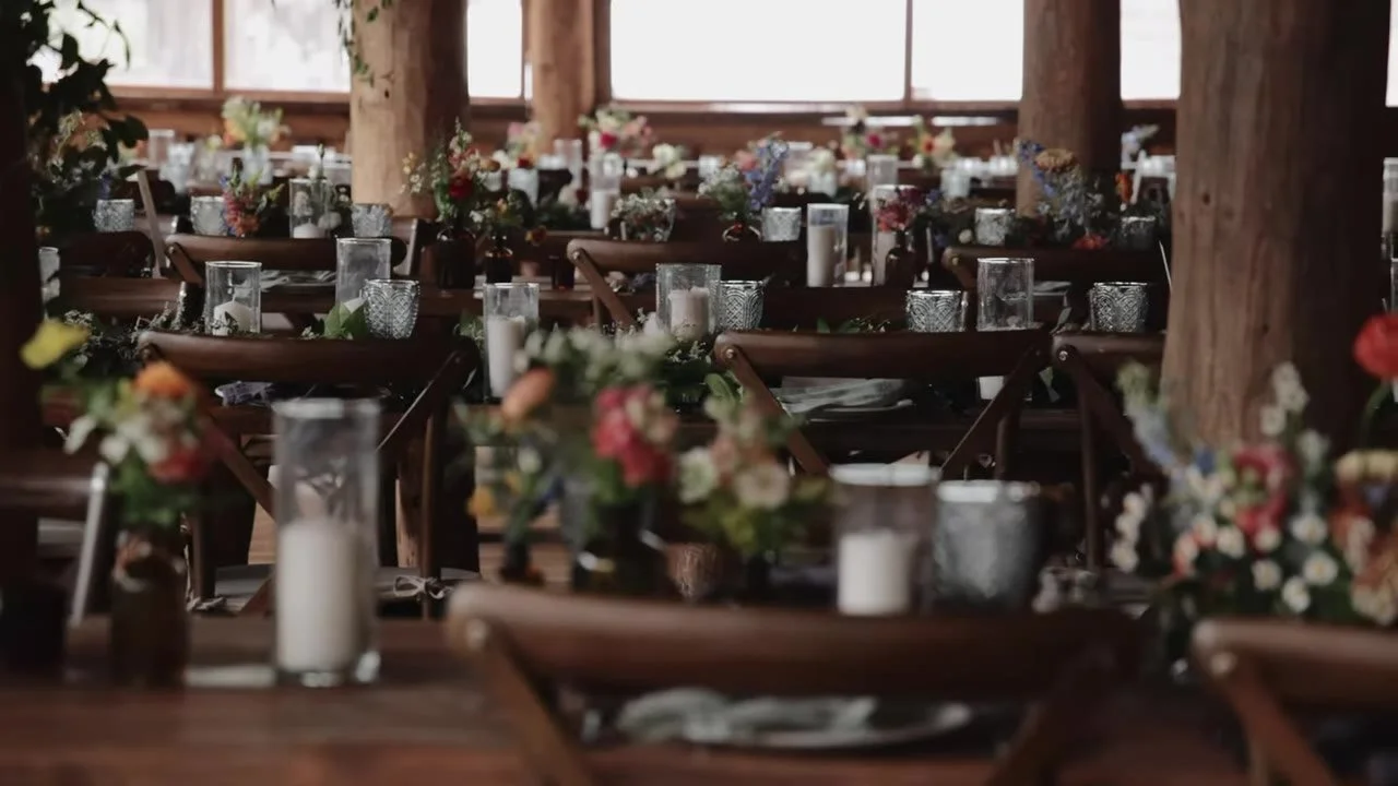 Lodge reception tables at Piney River Ranch with wildflowers, candles, and log posts