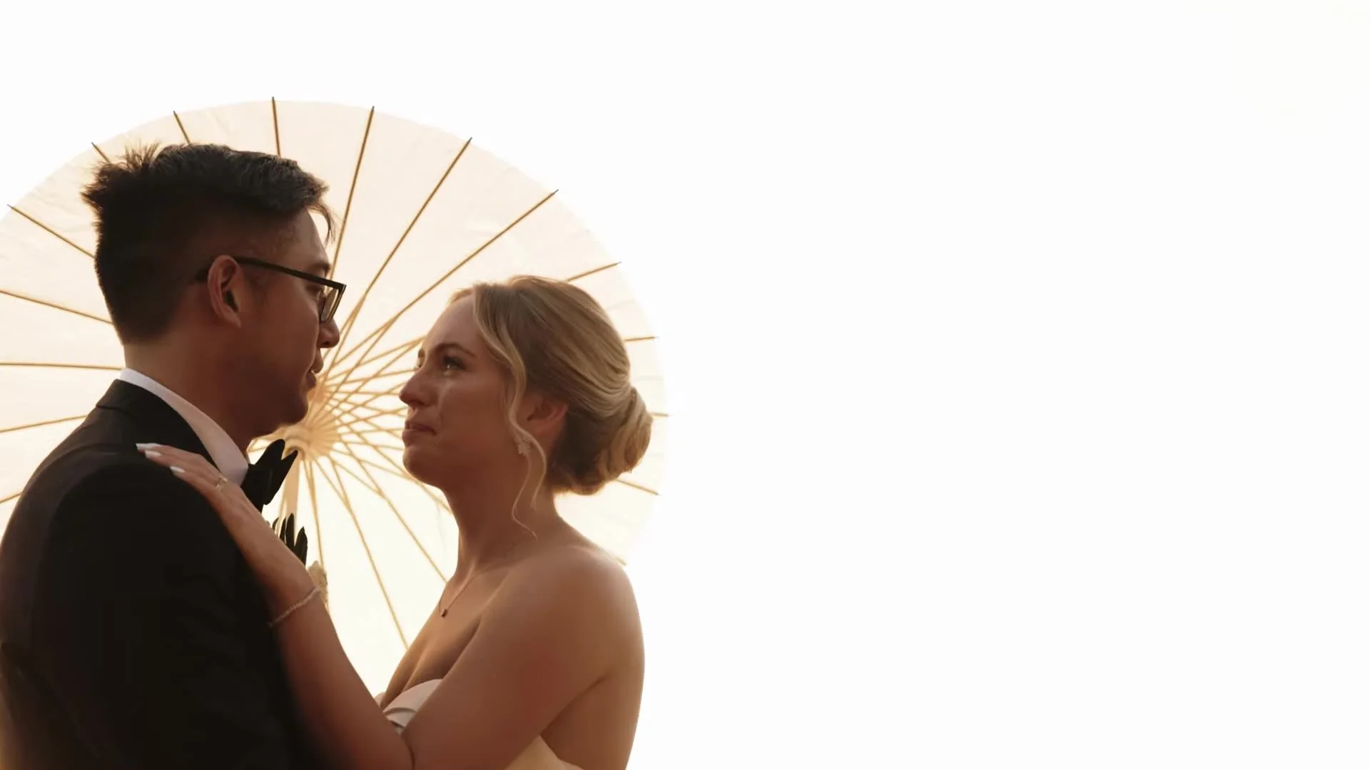 Jason and Rachel face to face under a paper parasol at Canyonwood Ridge in Dripping Springs, Texas