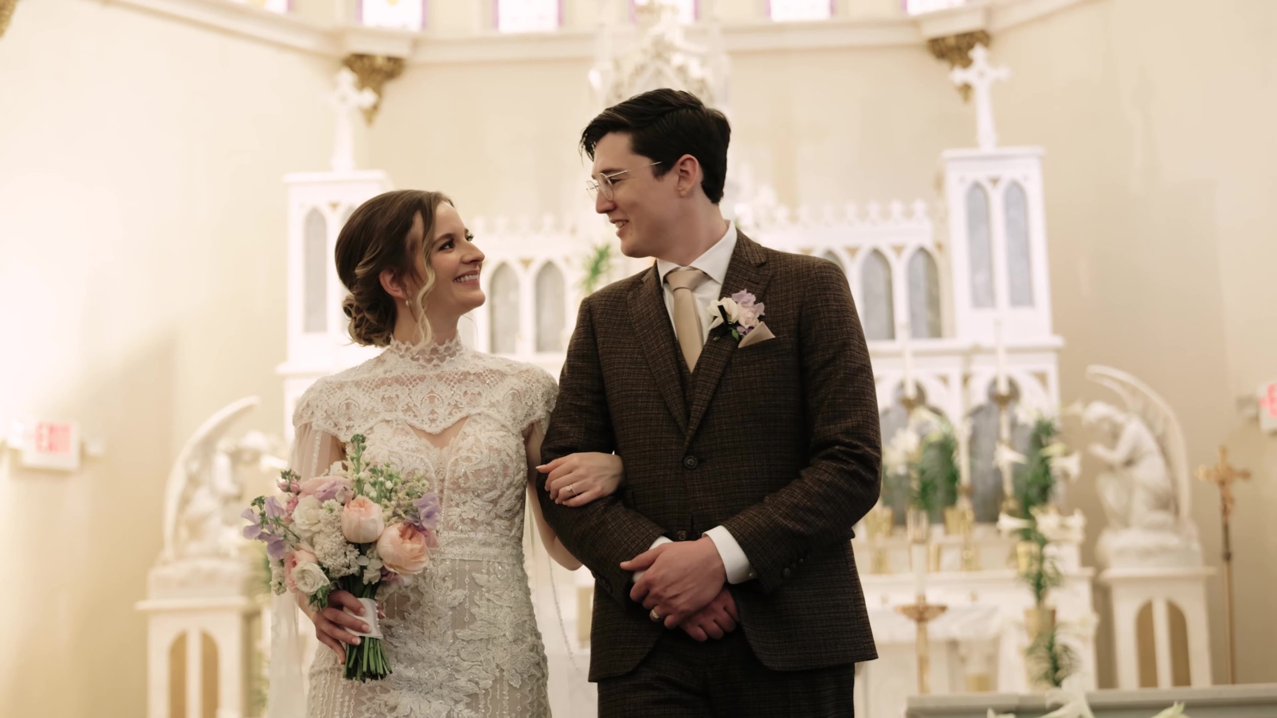 Bride in lace gown and groom in tweed suit smiling arm in arm at the altar in Houston, Texas