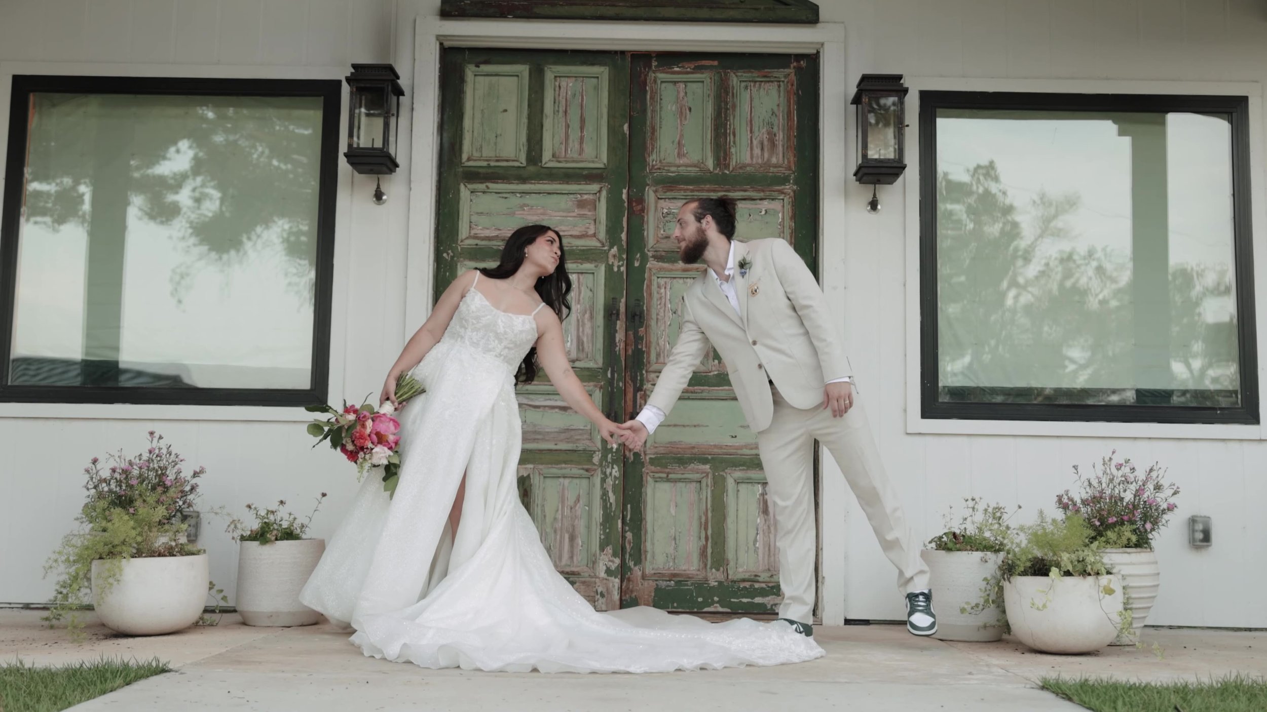 Peter and Kiyara holding hands in front of the wooden doors at Videre Estate near Austin Texas