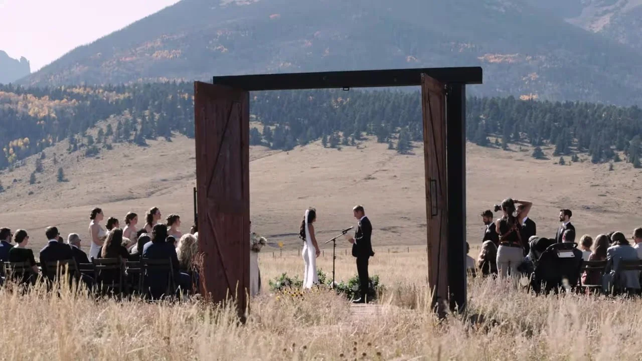 Justin and Sierra exchanging vows inside an open barn door frame in a meadow at 3 Peaks Ranch