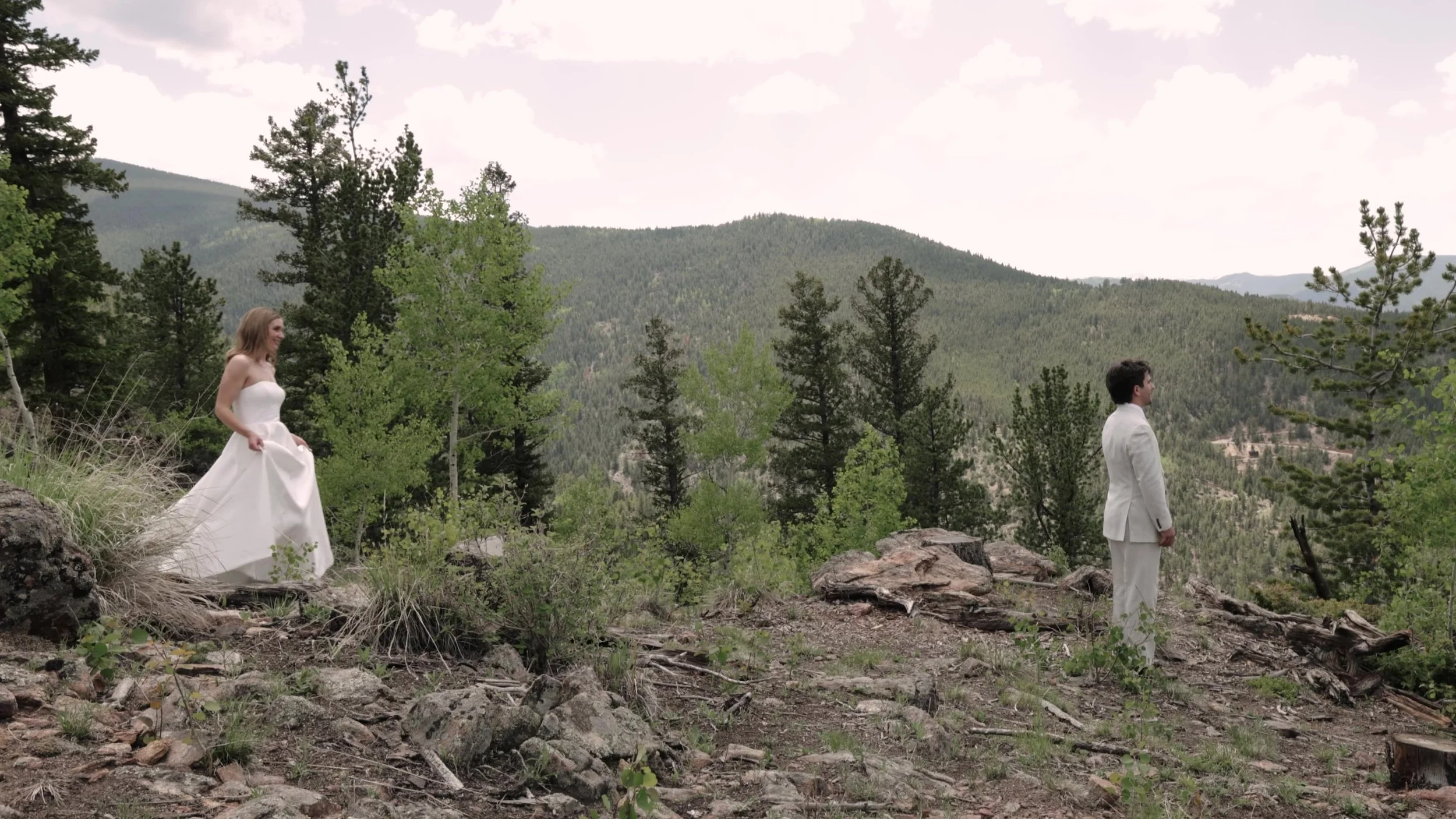 Bride and groom standing apart on a rocky pine hillside at Northstar Gatherings in Idaho Springs, Colorado