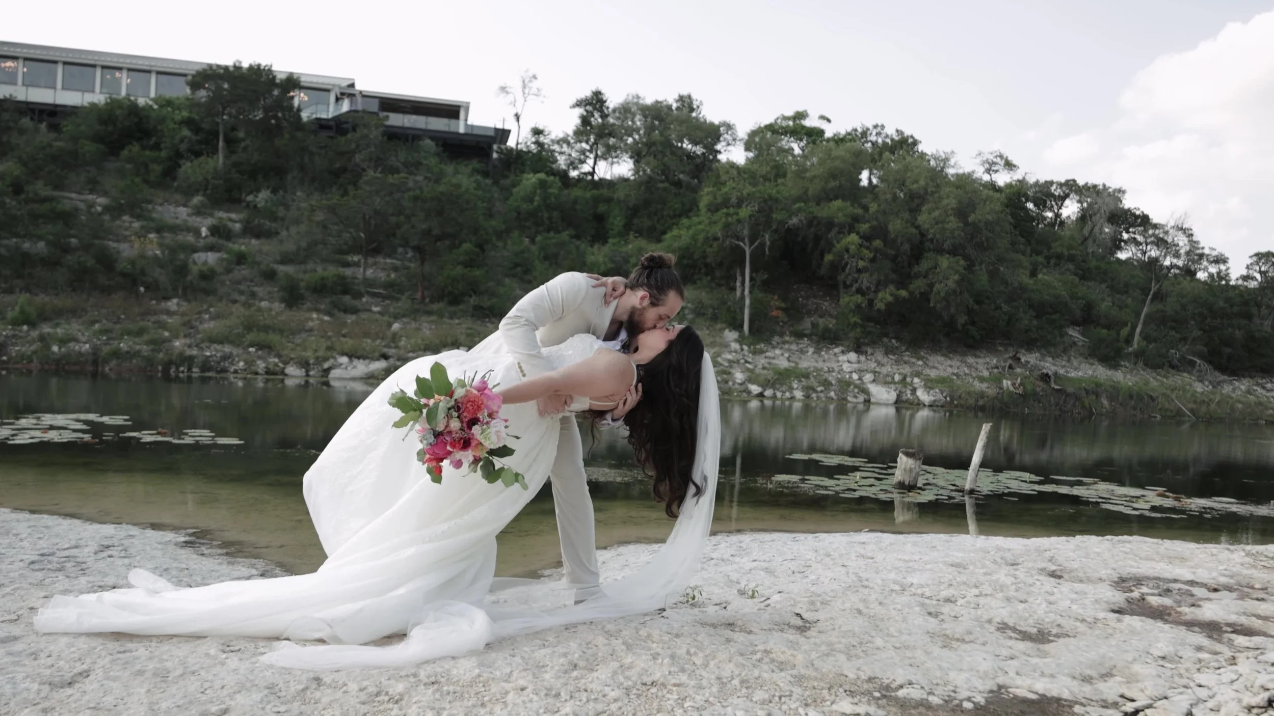 Peter dips Kiyara for a kiss on limestone by the water at Videre Estate Austin