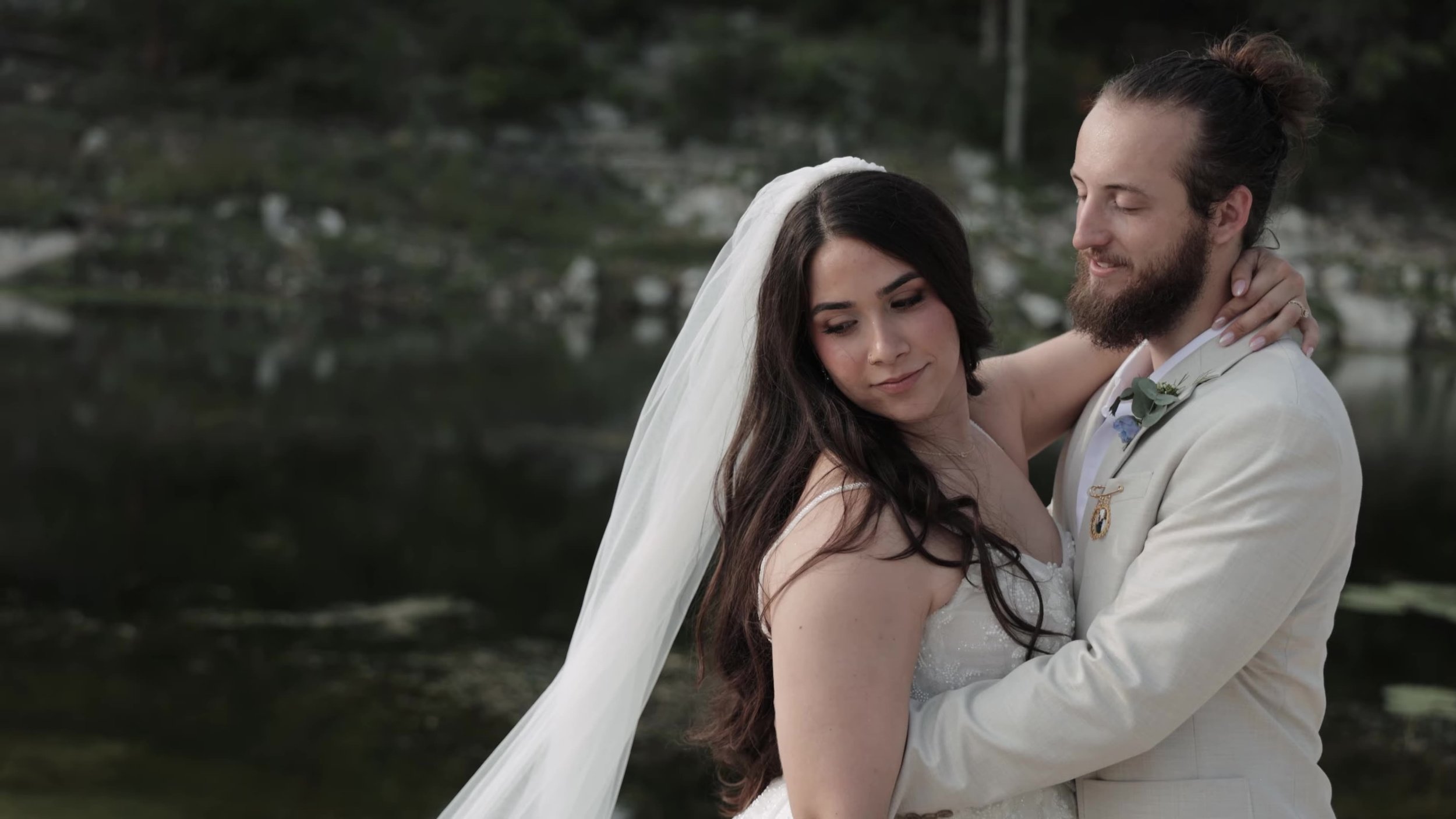 Peter and Kiyara embrace near the water at Videre Estate in the Texas Hill Country near Austin