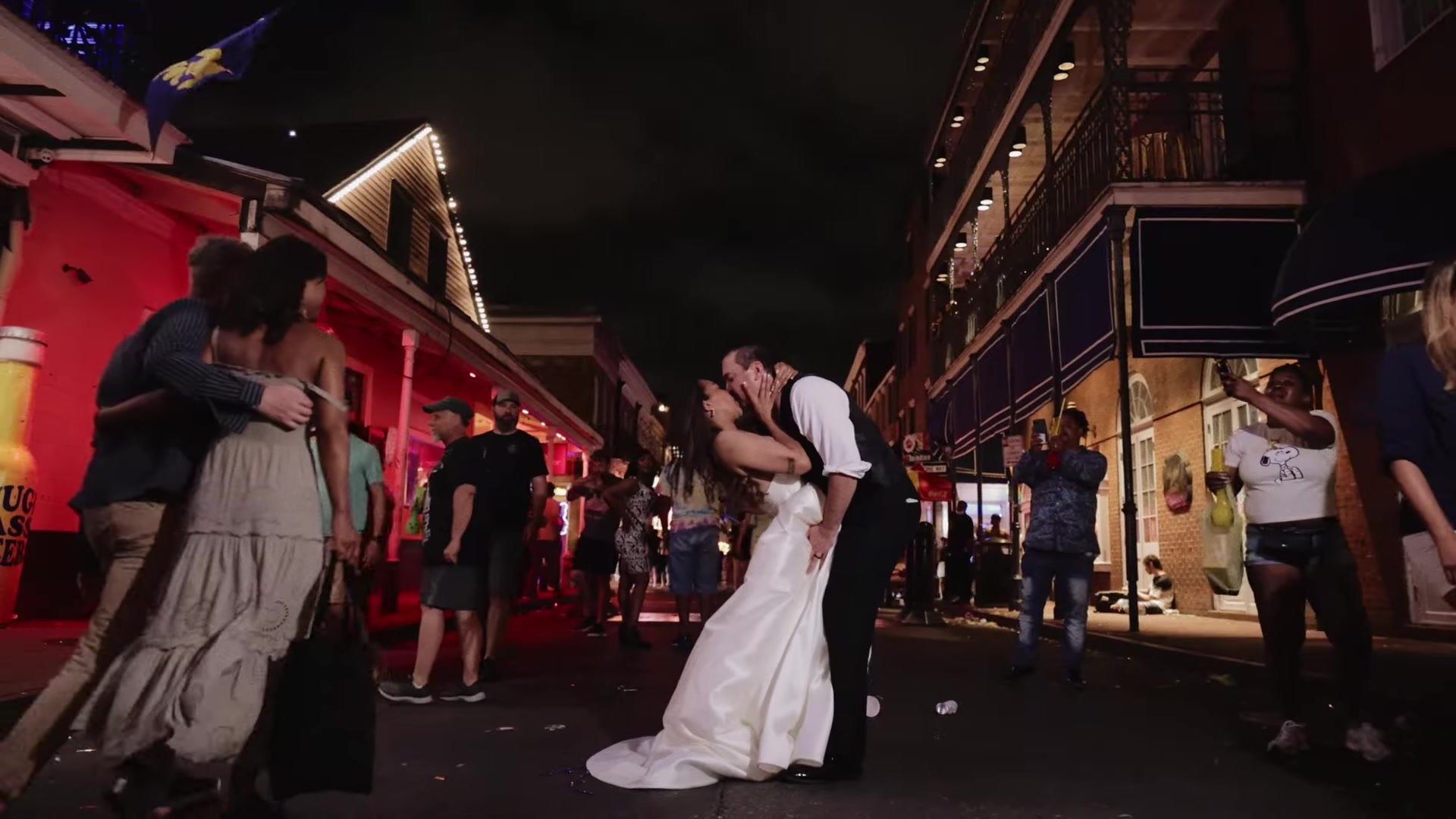 Blair and Gustavo dipping for a kiss on a crowded French Quarter street at night in New Orleans