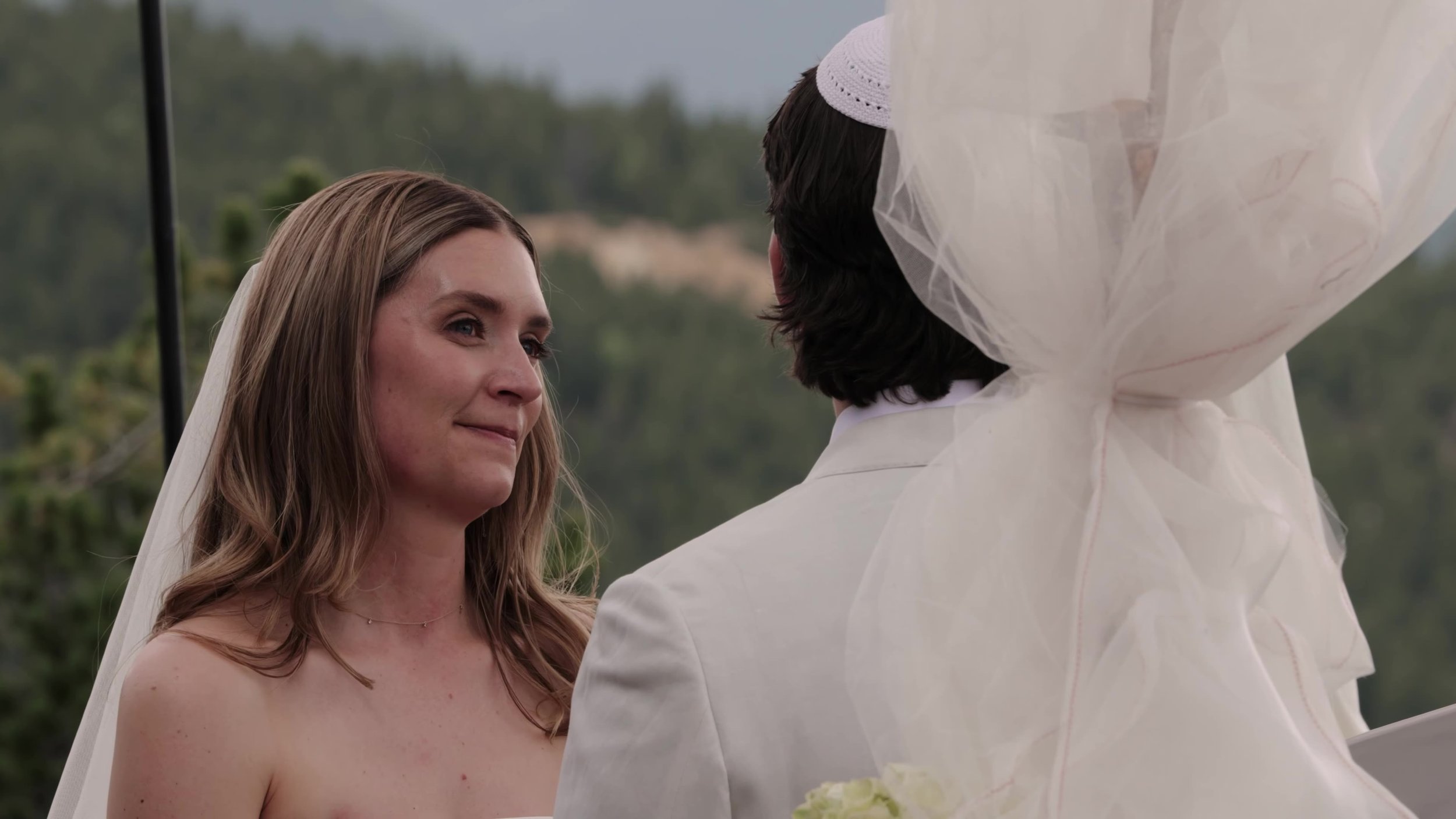 Bride looking at the groom during the ceremony at Northstar Gatherings in Idaho Springs, Colorado, mountains soft behind them
